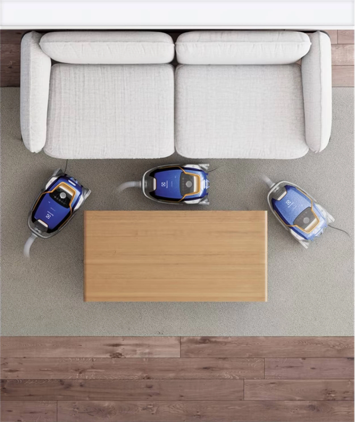 Widok z góry na trzy niebieskie odkurzacze w pobliżu drewnianego stolika kawowego i białej kanapy.