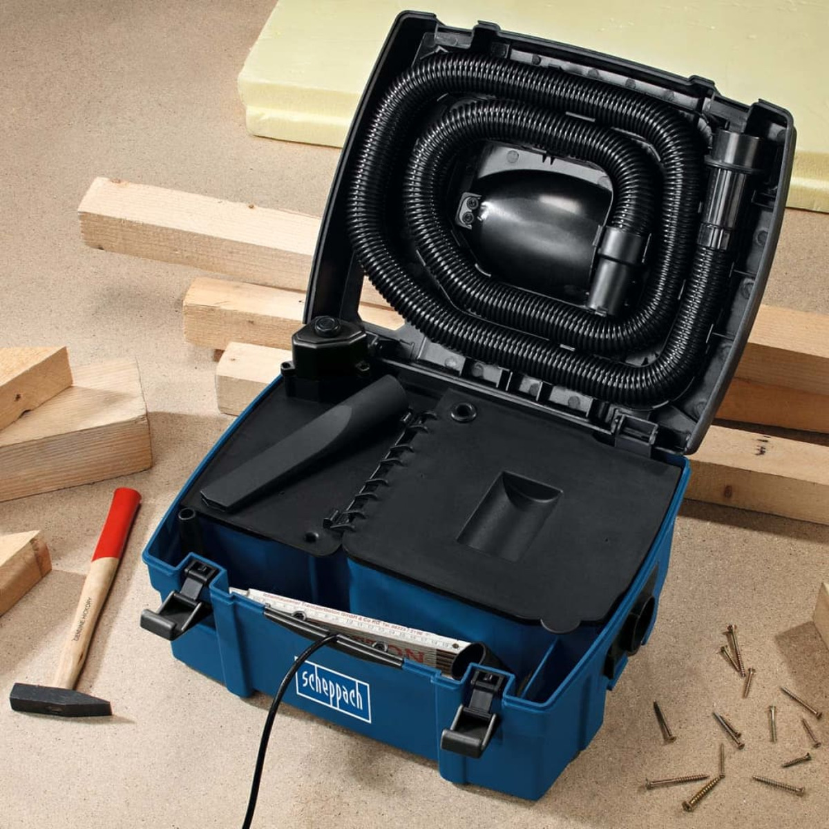 An open blue toolbox with tools, including a hammer and a measuring tape, on a wooden surface.