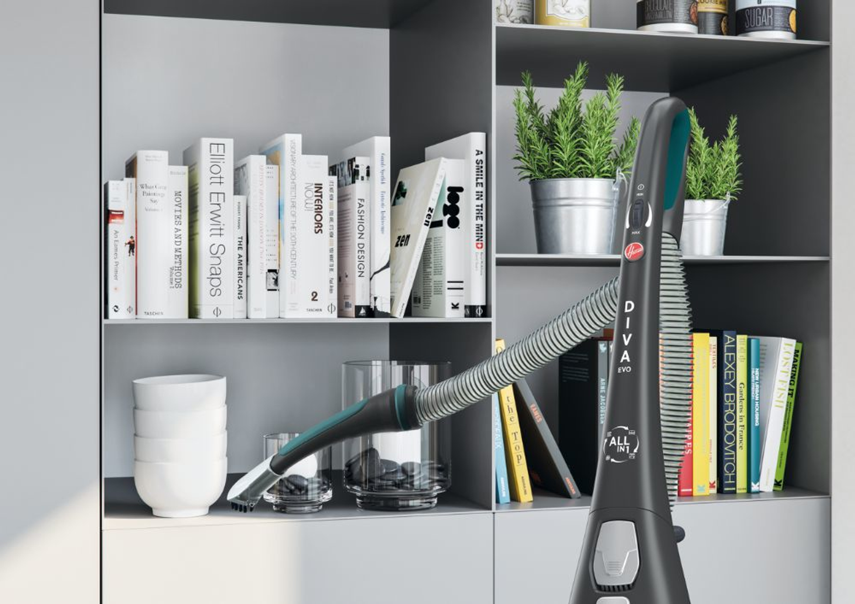 Un aspirapolvere e un tubo accanto a una libreria con libri, un vaso e piante in vaso.