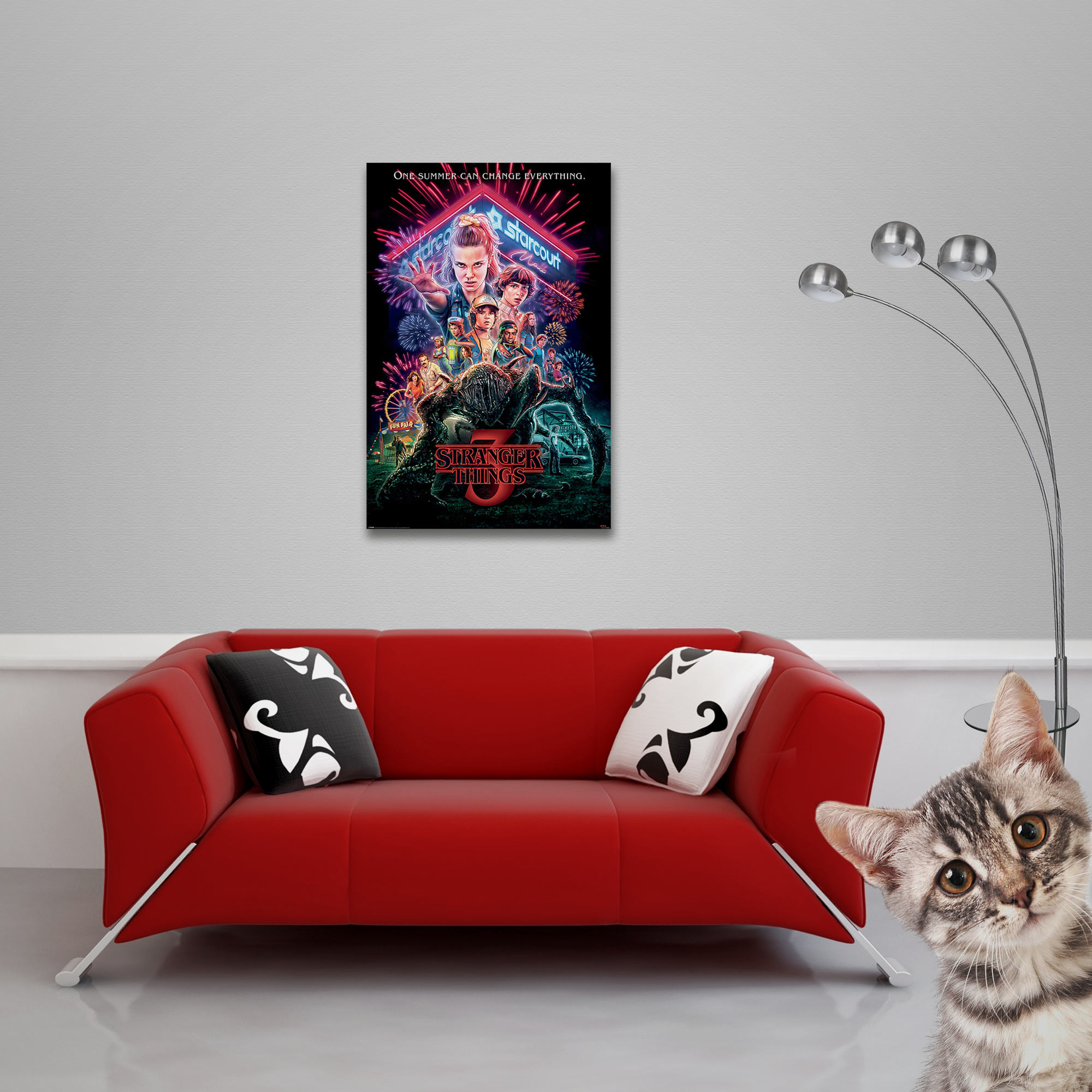 Ein Filmplakat an einer Wand, ein rotes Sofa, eine Katze schaut in die Kamera.