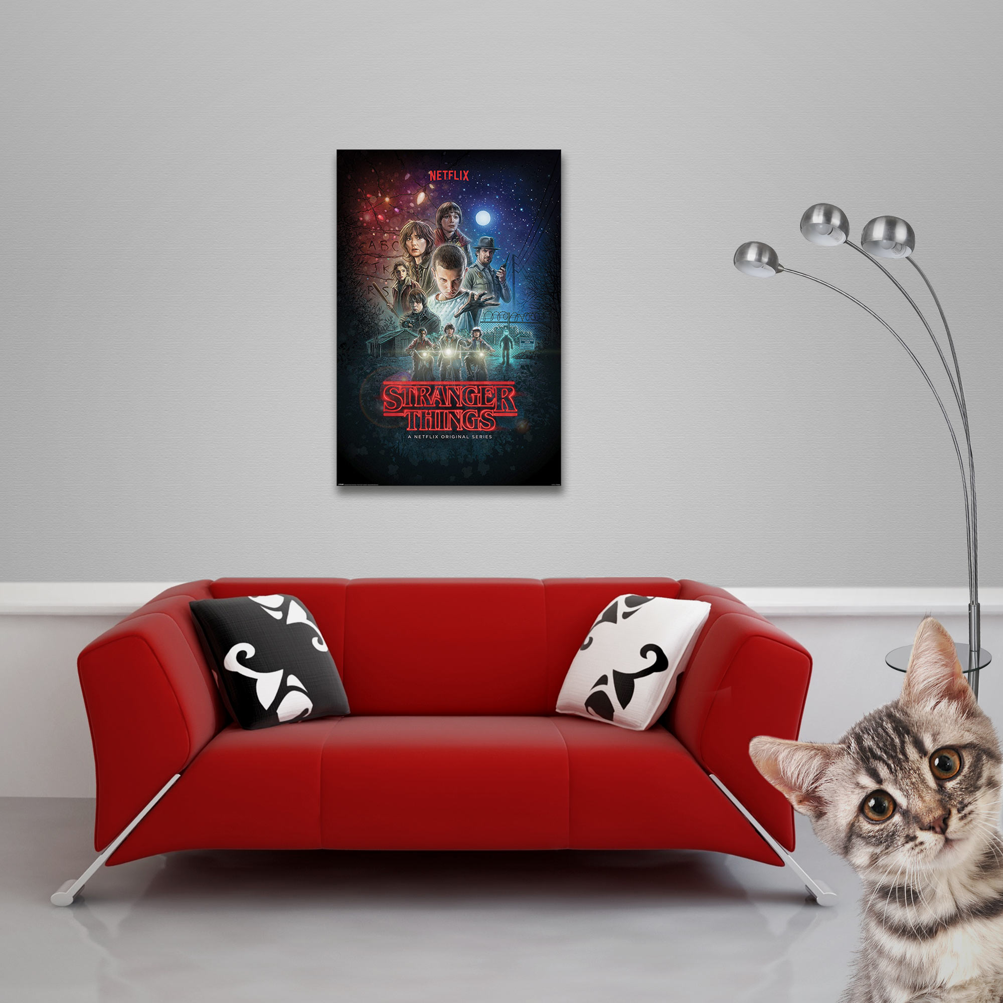 Stranger Things-Poster an einer Wand. Ein rotes Sofa und eine Katze, die in die Kamera schaut.