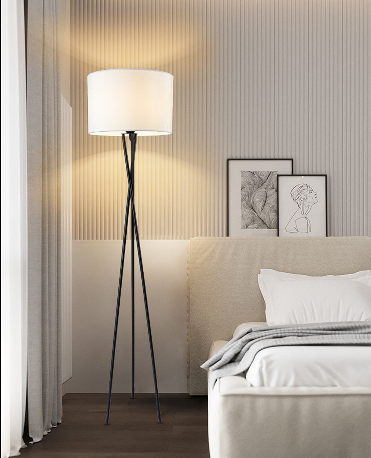 Eine Stehlampe mit weißem Schirm und schwarzen Beinen steht in einem Schlafzimmer.