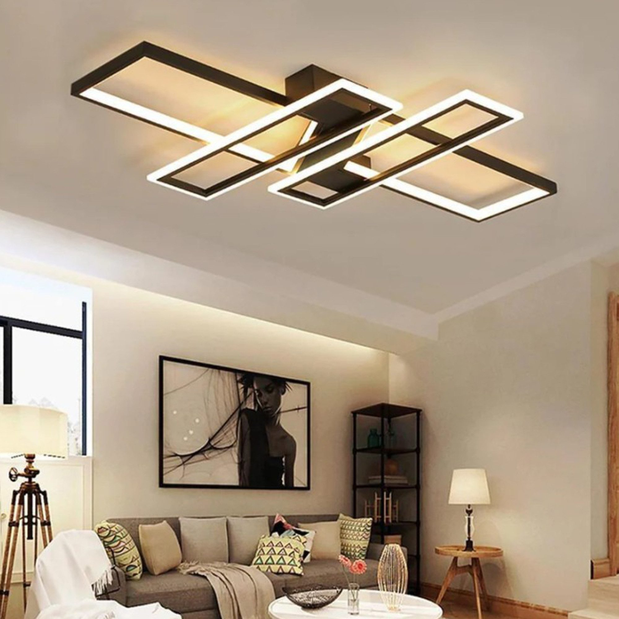 Eine moderne Deckenleuchte mit rechteckigen Paneelen. Sie hängt in einem Raum mit Sofa, Kunst und einer Lampe.