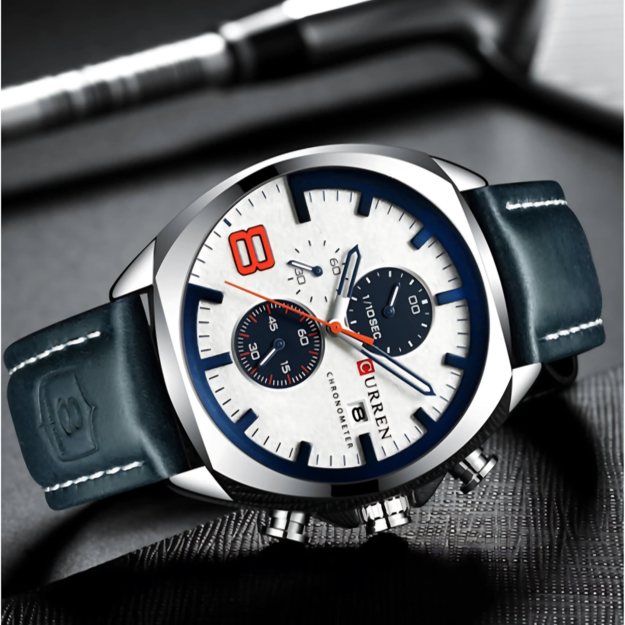 Eine silberne Uhr mit weißem Zifferblatt, schwarzen und blauen Zifferblättern und einem blauen Lederarmband.