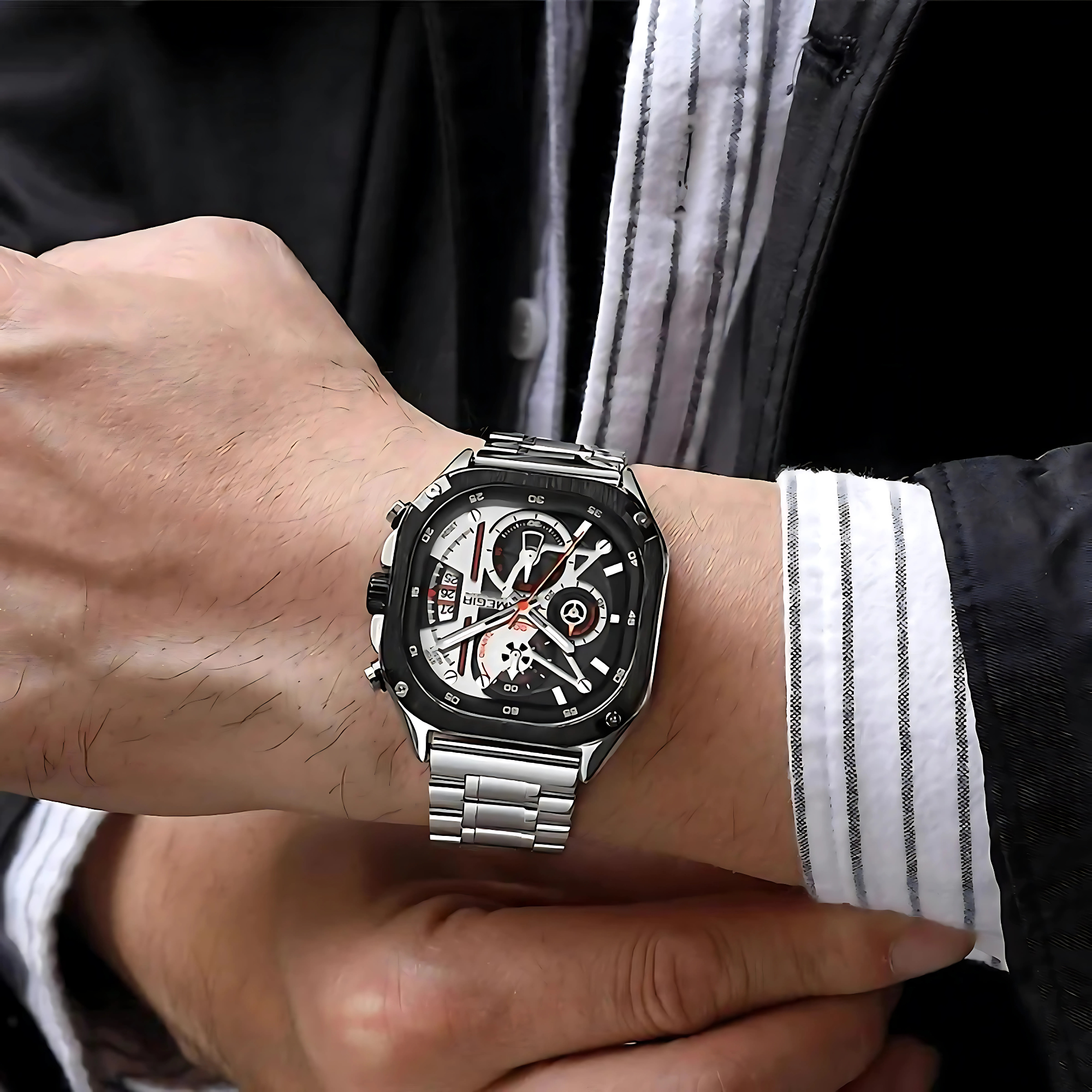 Handgelenk eines Mannes mit silberner Uhr. Die Uhr ist quadratisch, schwarz mit weißen und roten Akzenten.