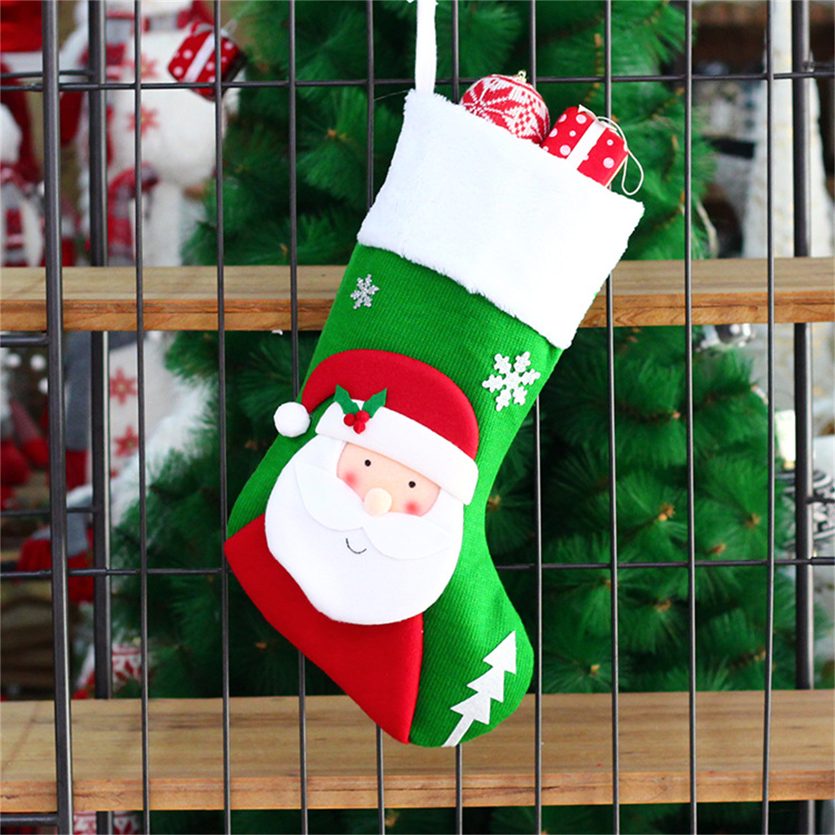 Ein Weihnachtsstrumpf mit Santa-Gesicht, Dekorationen und grünem Weihnachtsbaumhintergrund.