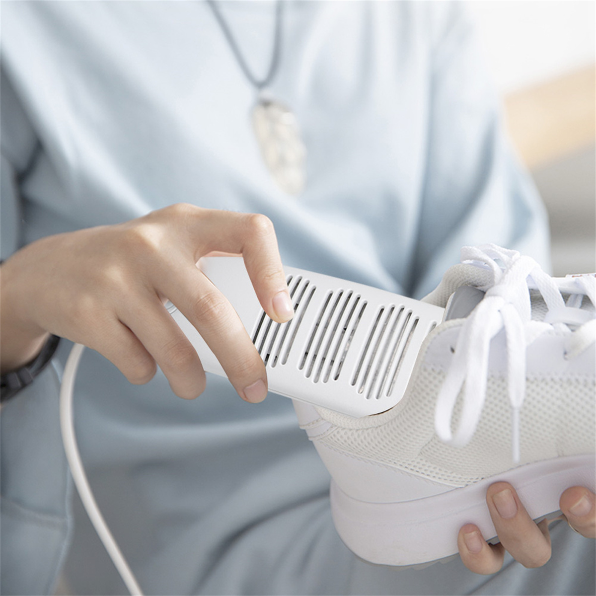 Person hält einen Schuh mit einem eingesetzten weißen Schuhtrockner.