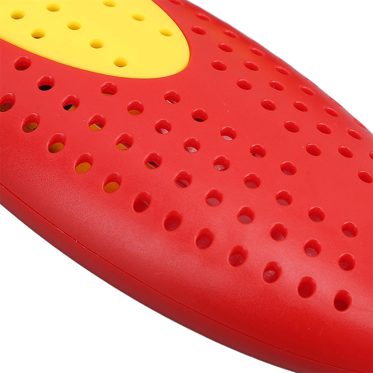 Nahaufnahme einer rot-gelben Kunststoffeinsatzes für Schuhe mit kleinen Löchern zur Belüftung.