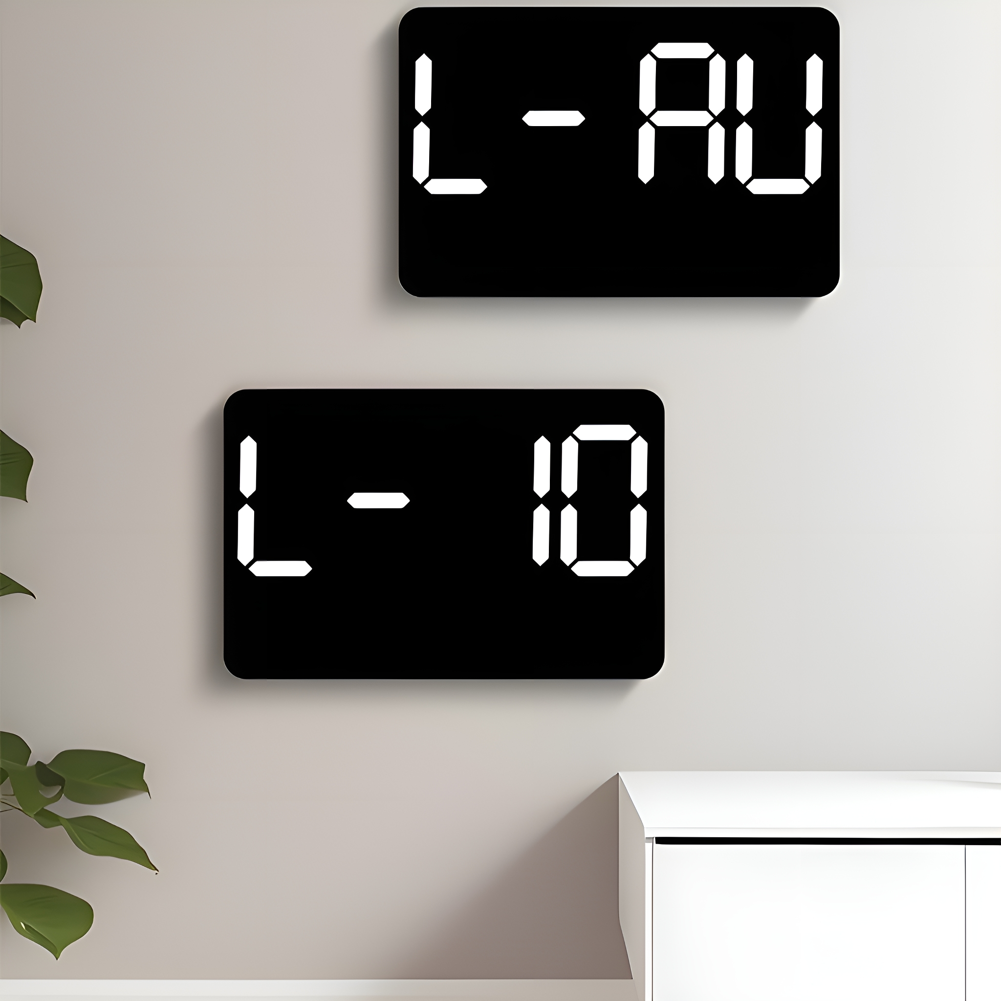 Zwei schwarze Digitaluhren mit weißen Zahlen. Eine zeigt 'L-AU', die andere 'L-10' vor einer hellen Wand.