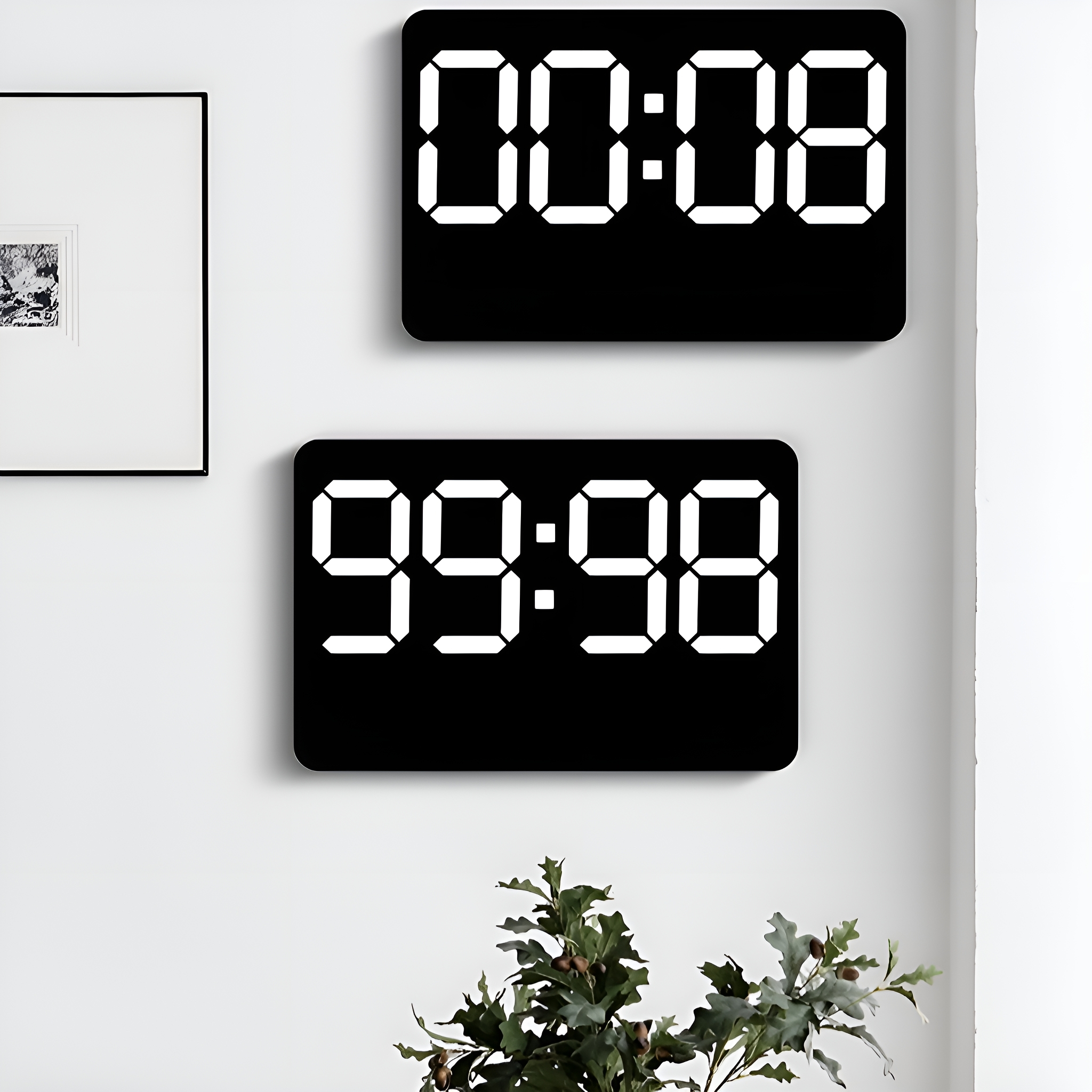 Zwei schwarze Digitaluhren an einer weißen Wand. Eine zeigt 00:08, die andere 99:98.