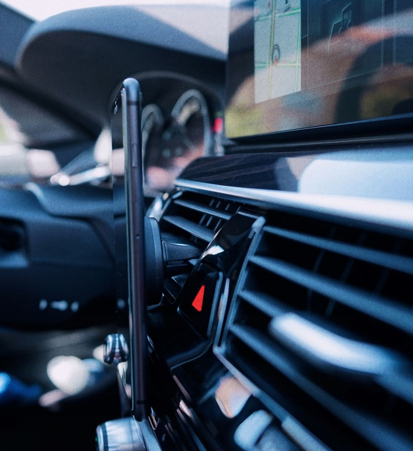 Telefon in einer Autolüftungshalterung. Innenraum eines Autos, Armaturenbrett sichtbar.