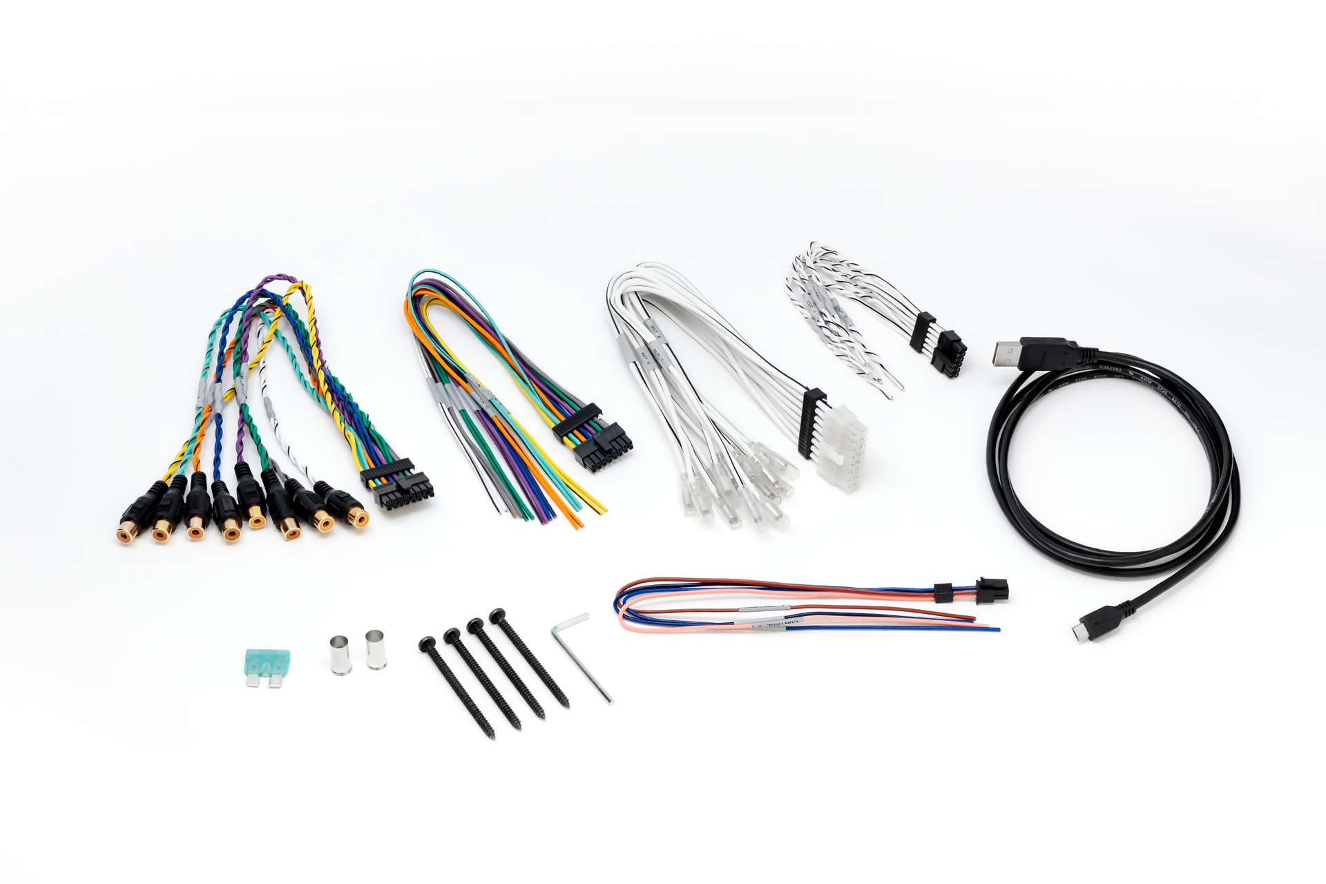 Verschiedene Autolautsprecher-Verkabelungskomponenten auf weißer Oberfläche. Kabel, Stecker, Schrauben, Sicherung.