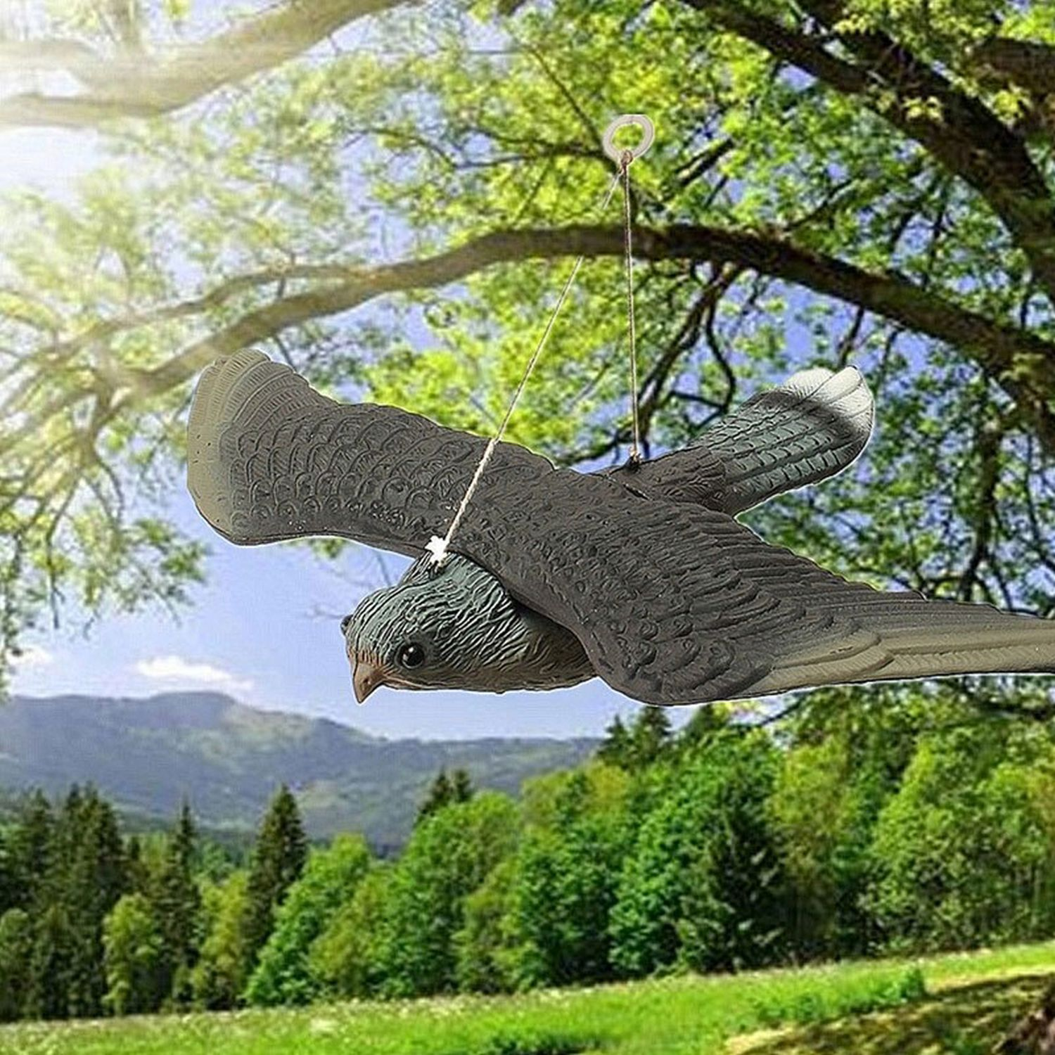 Un'esca a forma di uccello appesa a un ramo contro uno sfondo naturale verde.