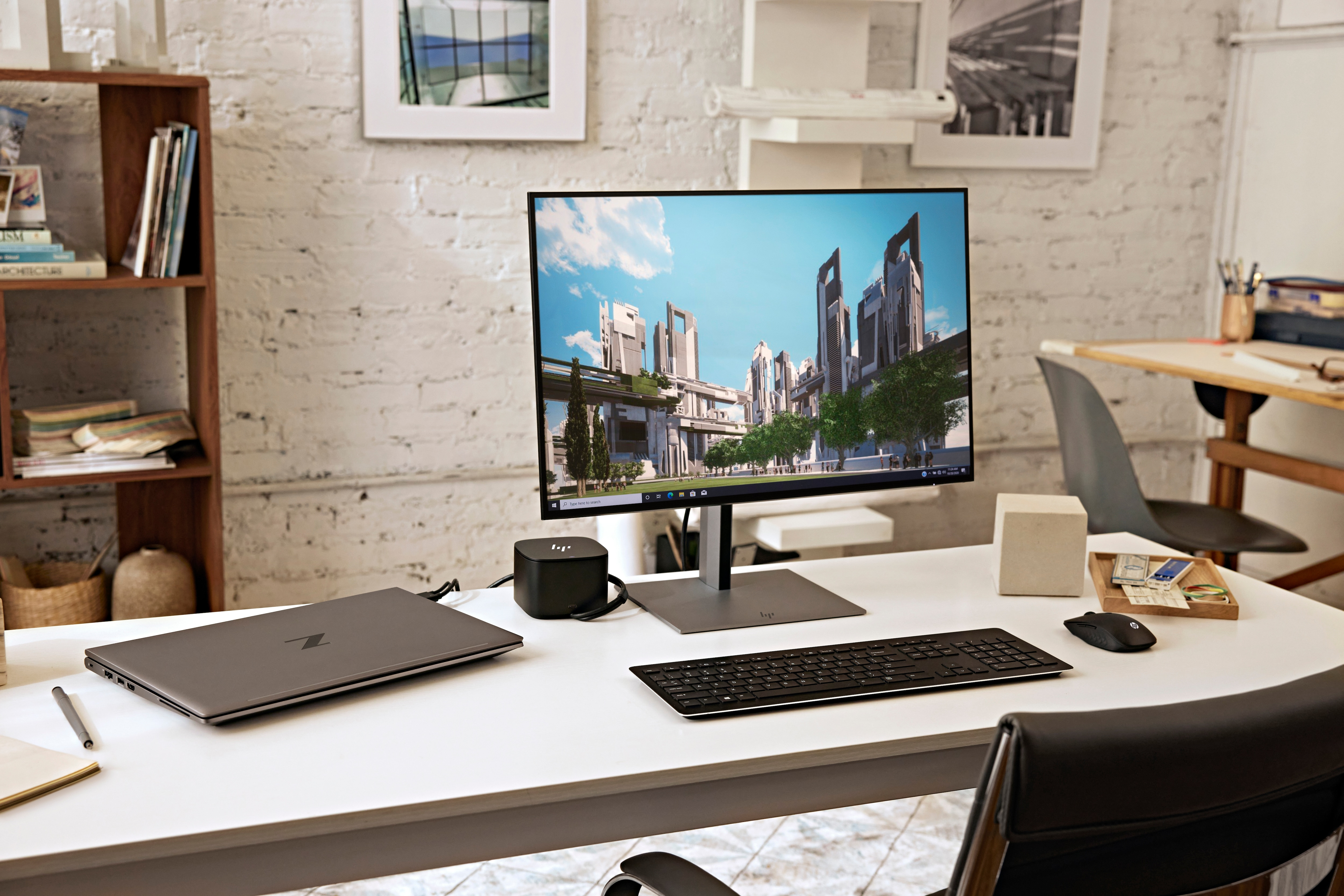 Bürotisch mit Monitor, der Stadtgebäude zeigt, Laptop, Tastatur, Maus und Schreibtisch-Organizer.