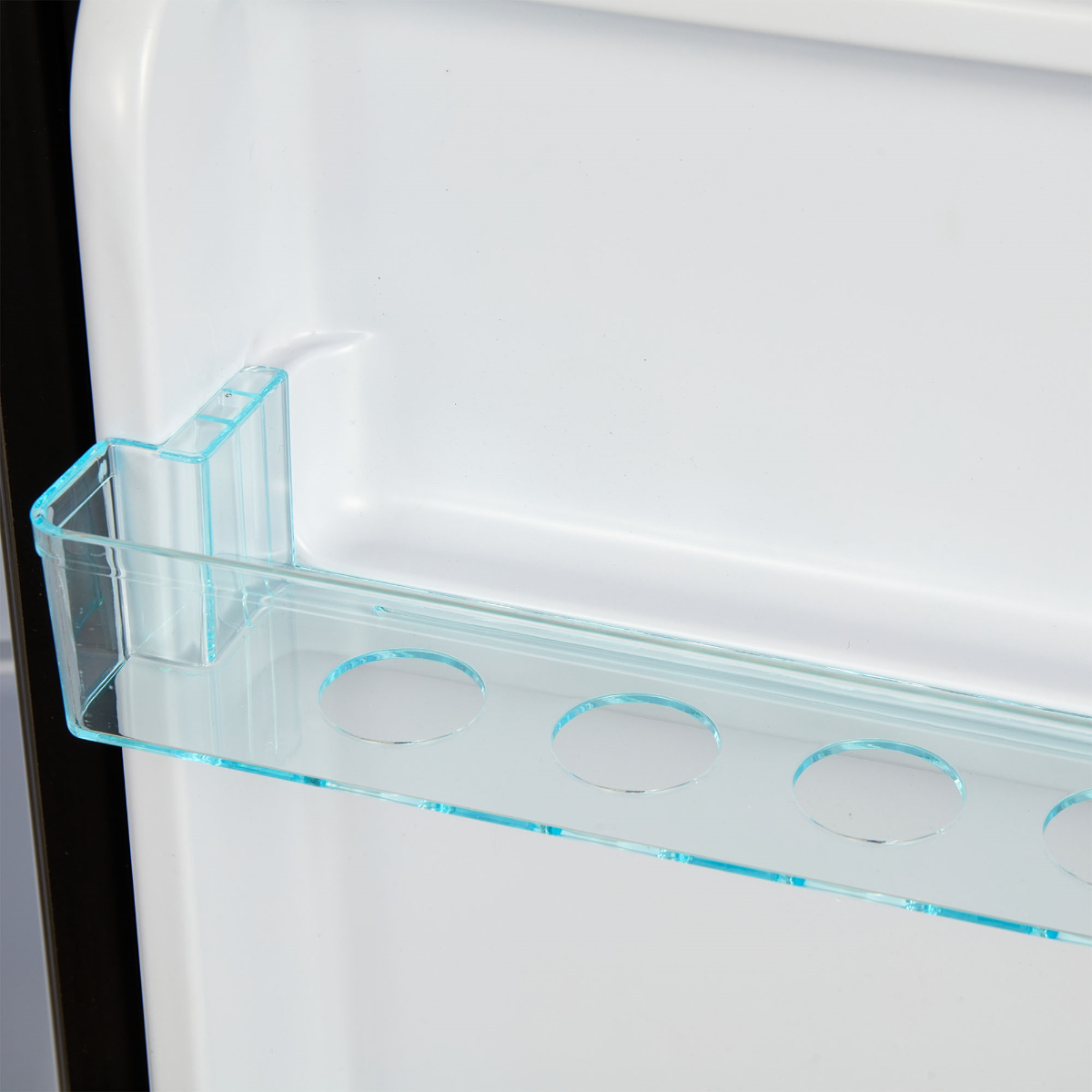 Ein durchsichtiges Regal in einem Kühlschrank mit Löchern für Flaschen. Der Hintergrund ist weiß.