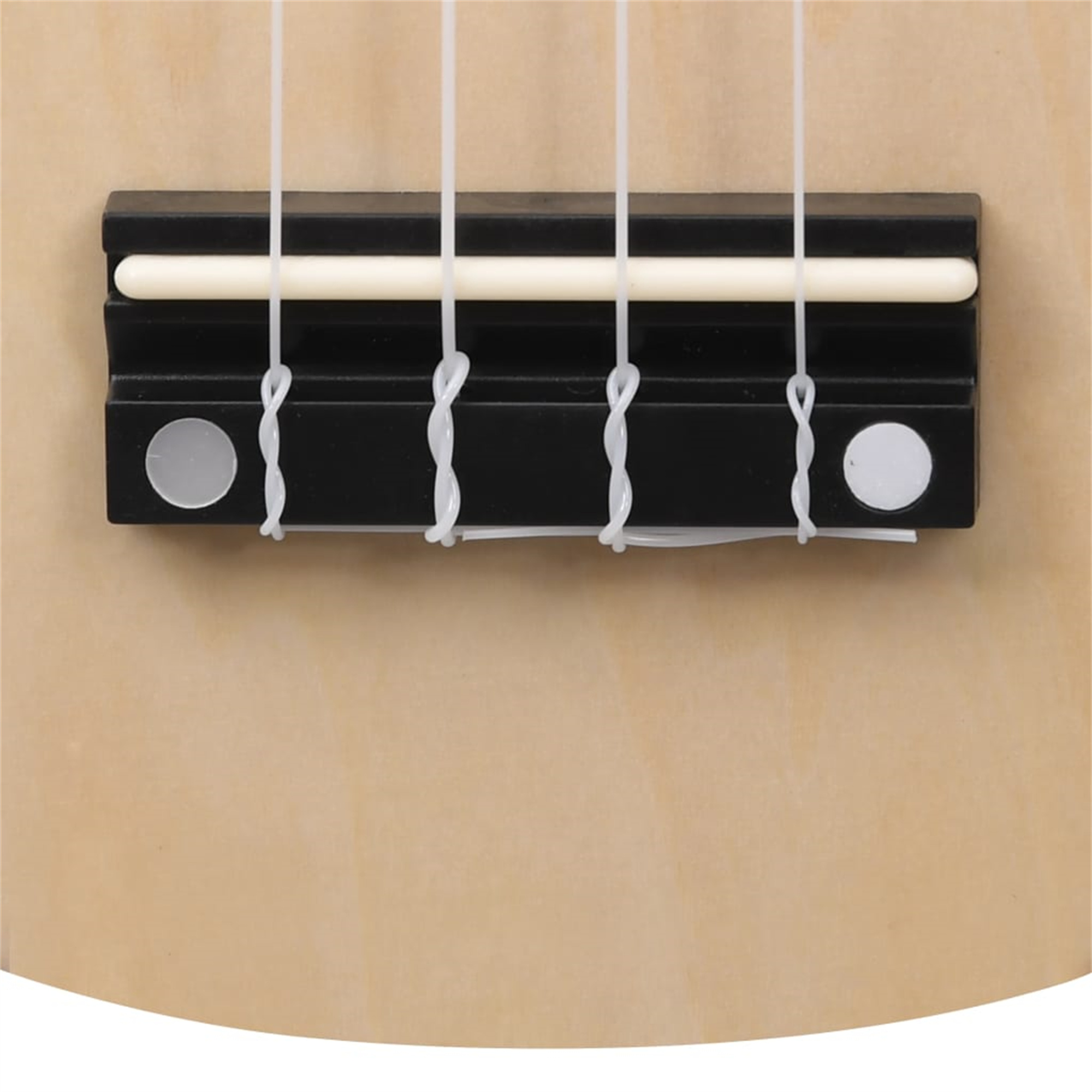 Nahaufnahme einer Ukulele-Brücke mit vier weißen Saiten, schwarzer Brücke und hellem Holz.