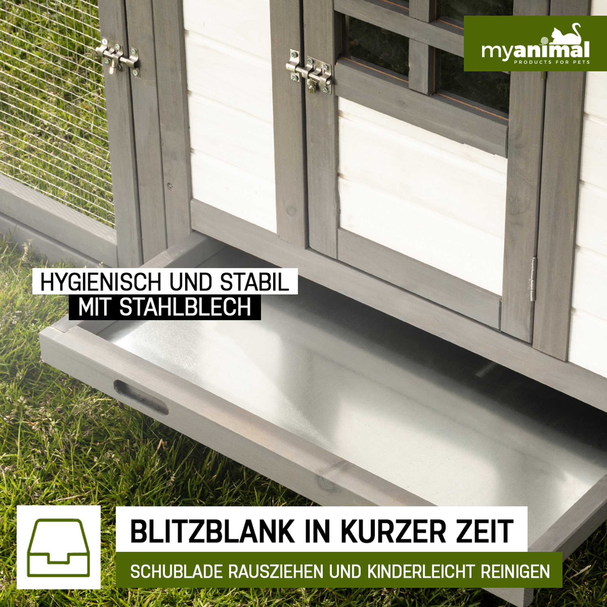 Ein hölzernes Tierhaus mit Metallwanne, Gras im Hintergrund.