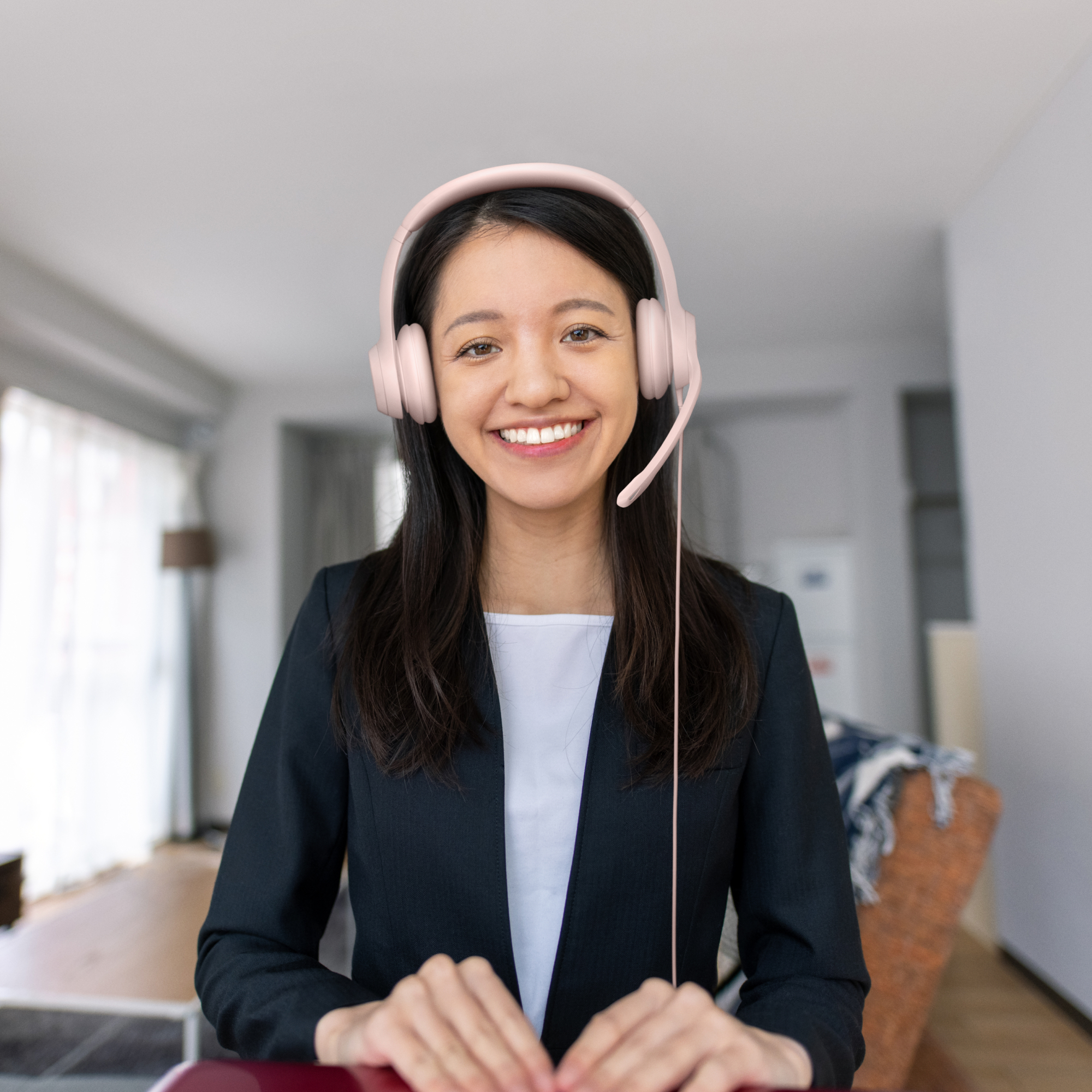Lächelnde Frau mit Headset, im Anzug, schaut in die Kamera.