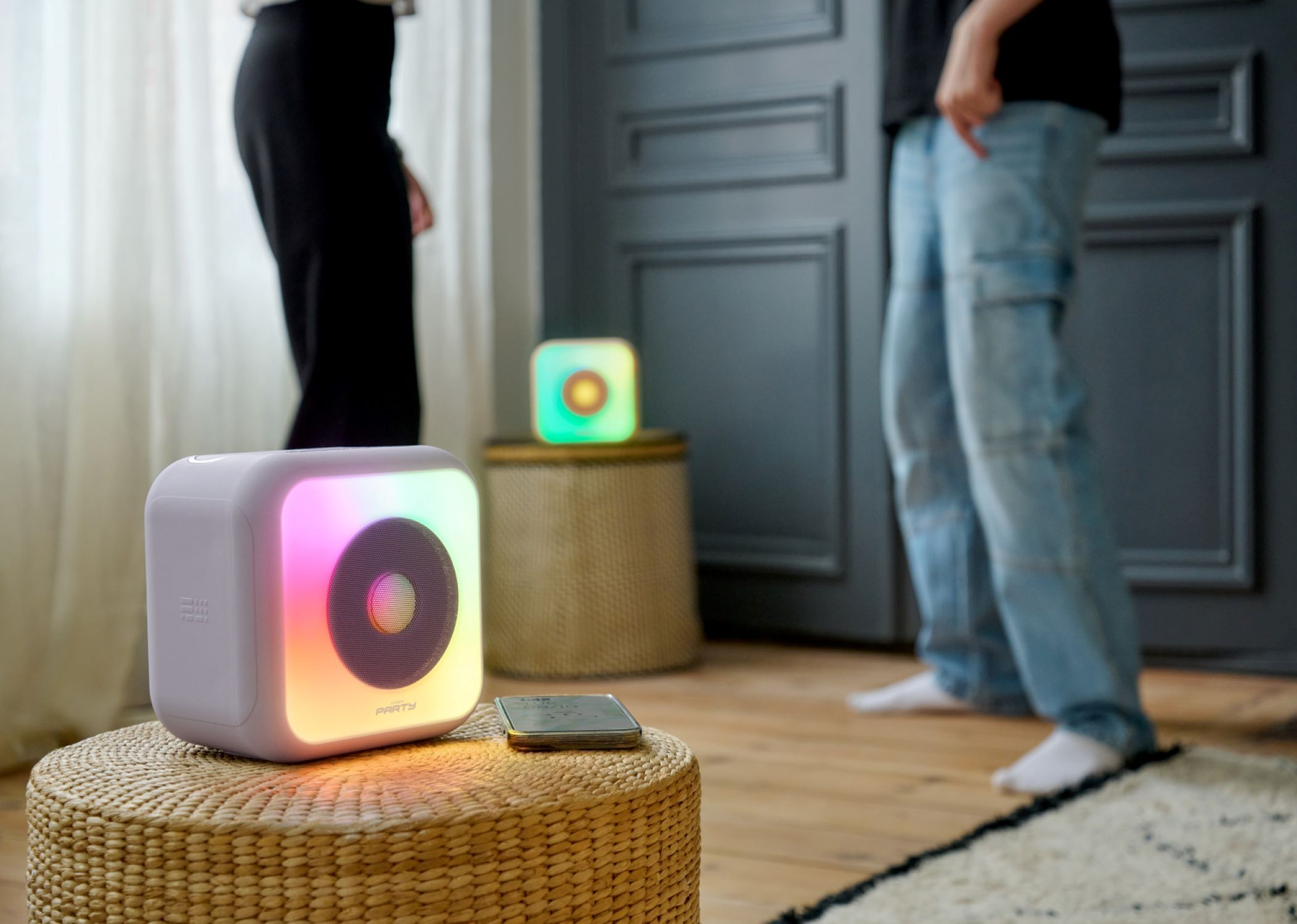 Dos personas con altavoces iluminados, una mesa con teléfono y una ventana.