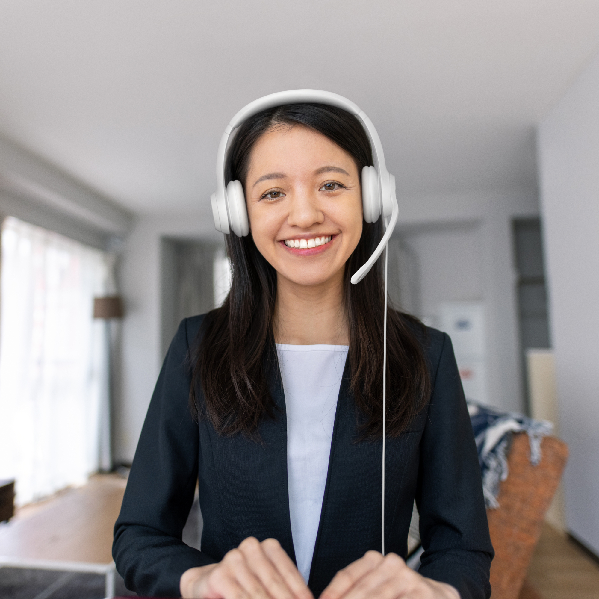 Vrouw in blazer met headset, lachend. Lichte kamer achtergrond.