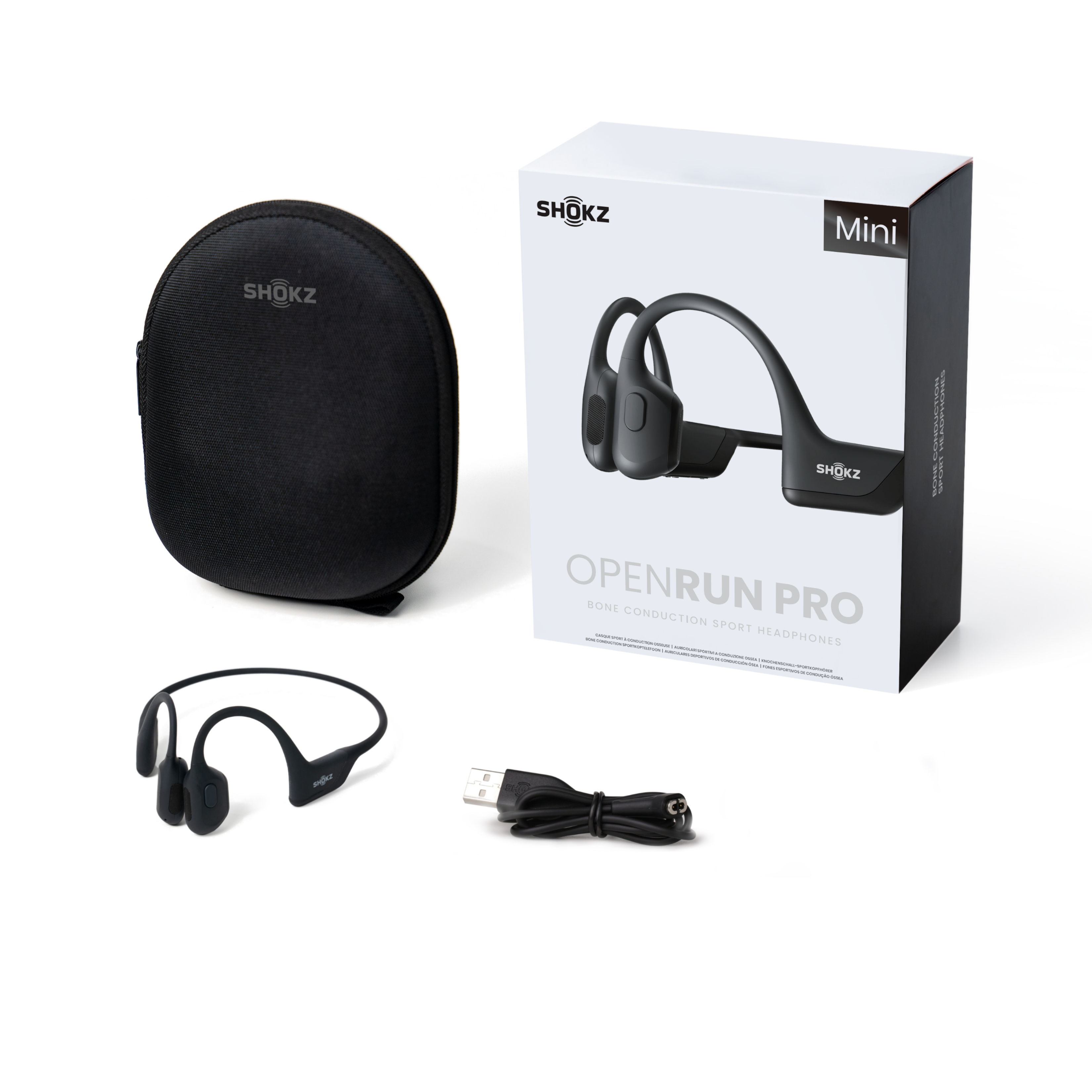 Czarne słuchawki Shokz z przewodnictwem kostnym, etui i pudełko z kablem ładującym na białym tle.