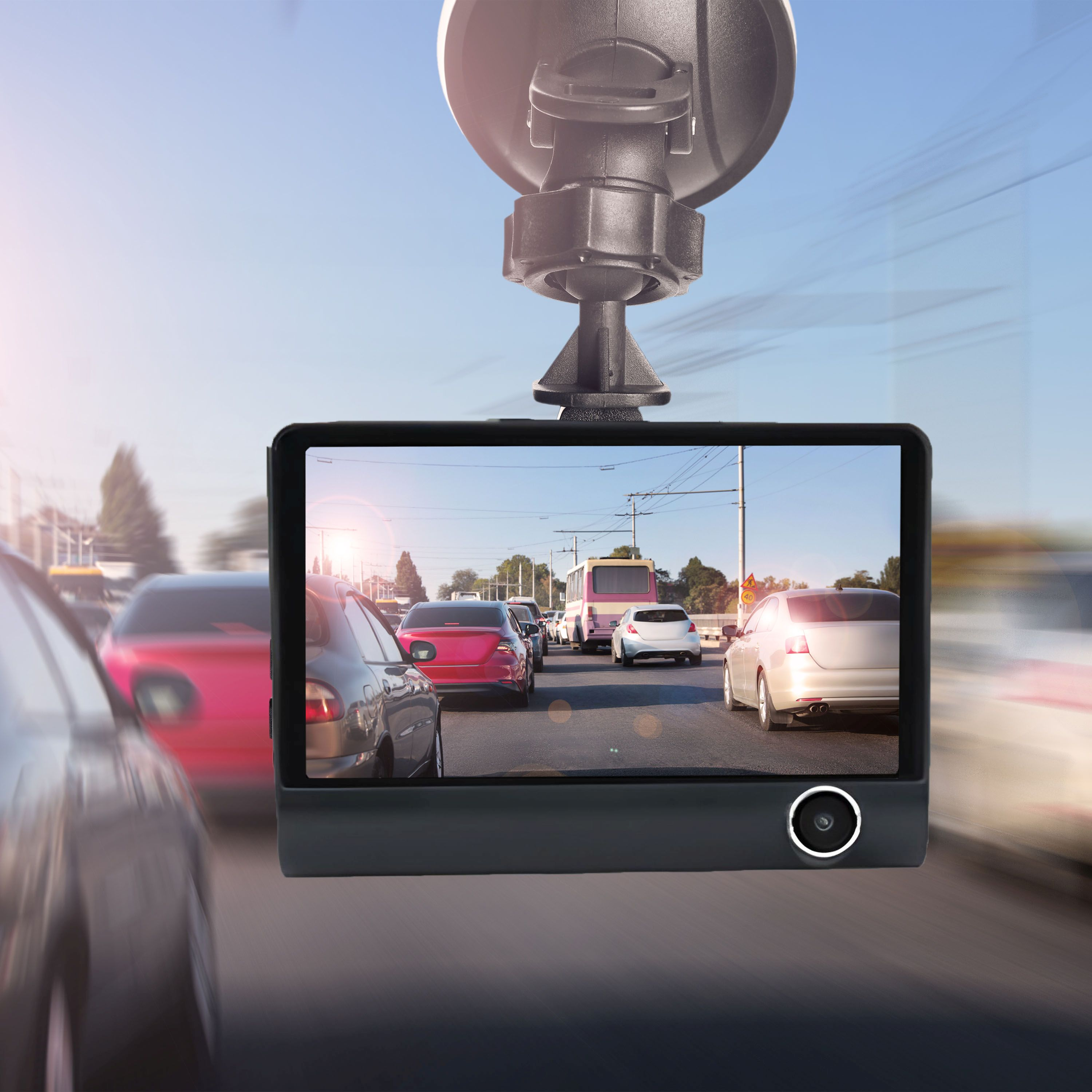Am Windschutzscheibe montierte Dashcam, zeigt Verkehr an einem sonnigen Tag. Autos, Bus und Straße sichtbar.