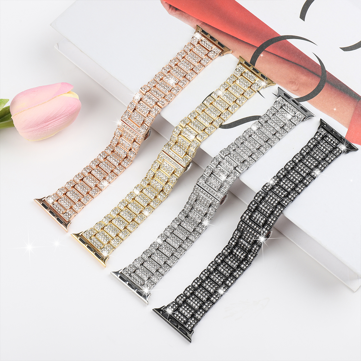 Vier glitzernde Uhrenarmbänder in verschiedenen Metallfarben mit Diamantbesatz.