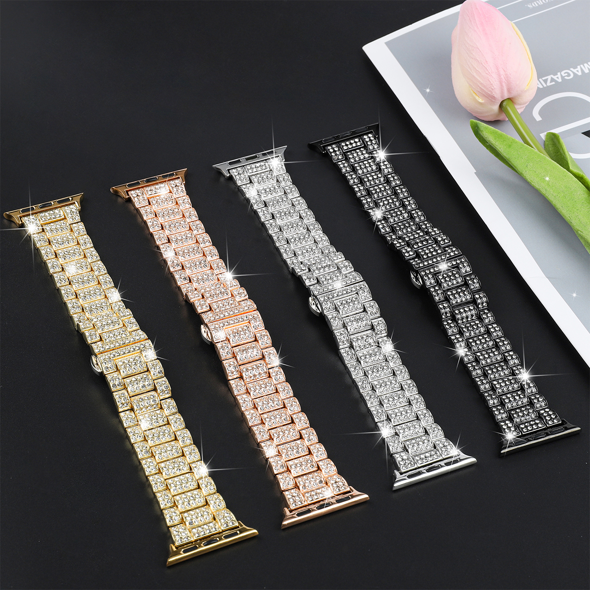Vier geschmückte Armbänder in Gold, Roségold, Silber und Schwarz, auf dunkler Oberfläche ausgestellt.