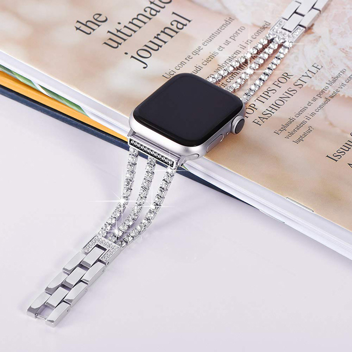 Silberne Apple Watch mit diamantbesetztem Armband auf einer Magazinseite.