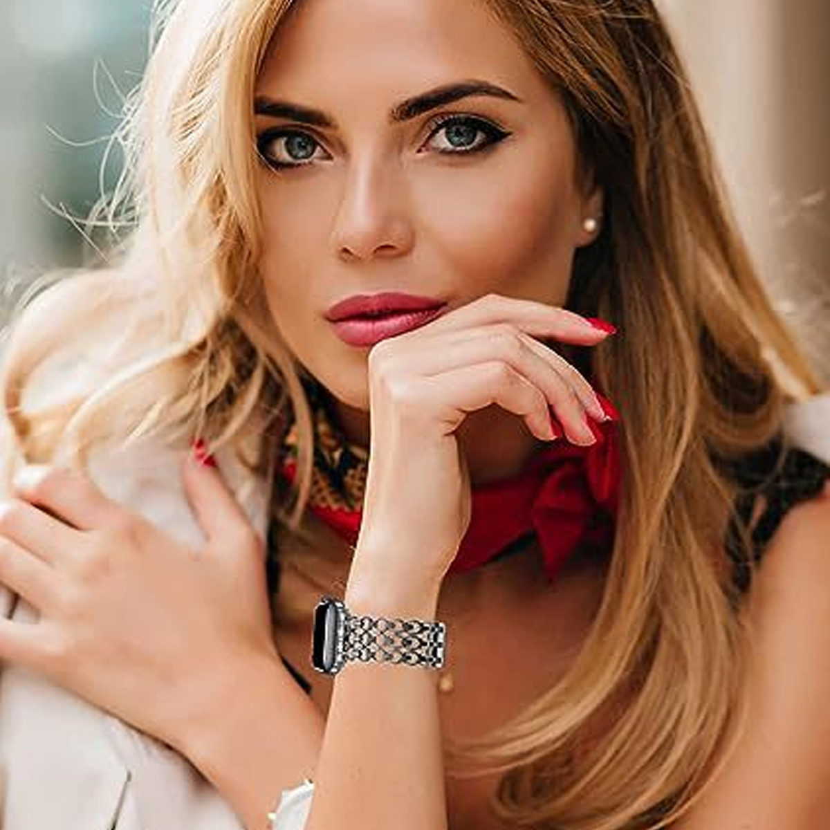 Blonde Frau mit silberner Armbanduhr und rotem Schal.