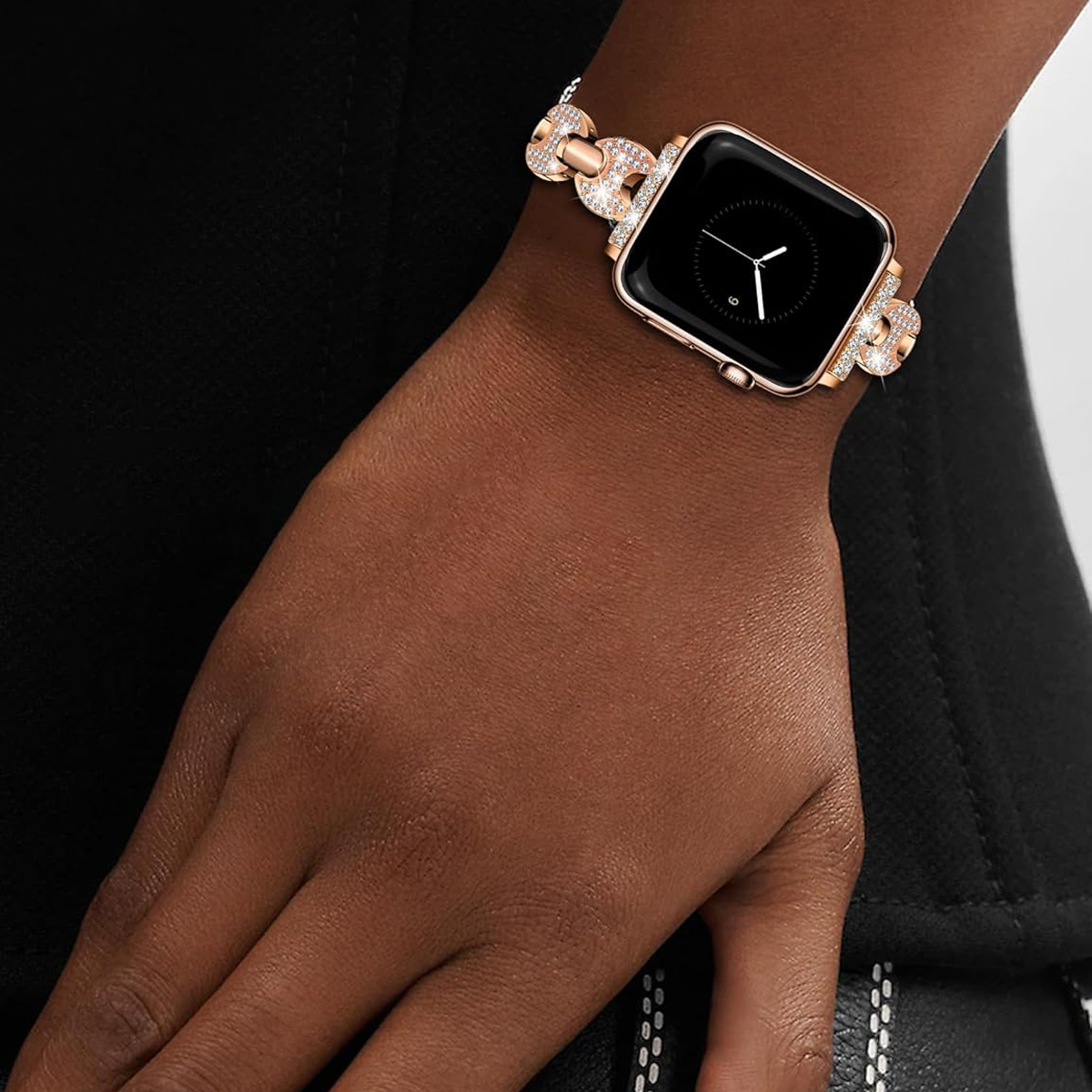 Handgelenk einer Frau mit einer roségoldenen Apple Watch mit diamantbesetztem Armband.