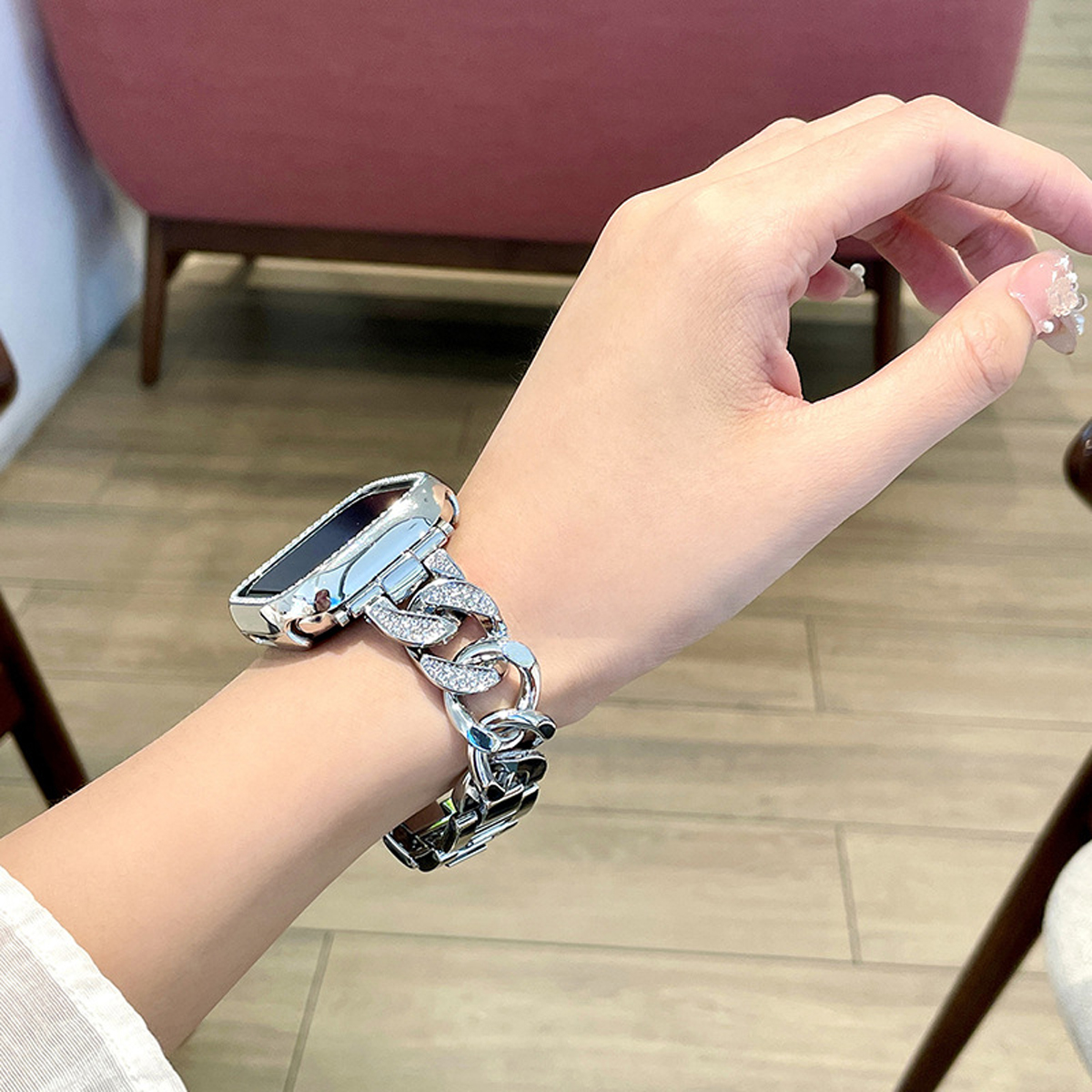 Eine Hand, die eine silberne Uhr mit einem Armband in Kettengliedoptik trägt.