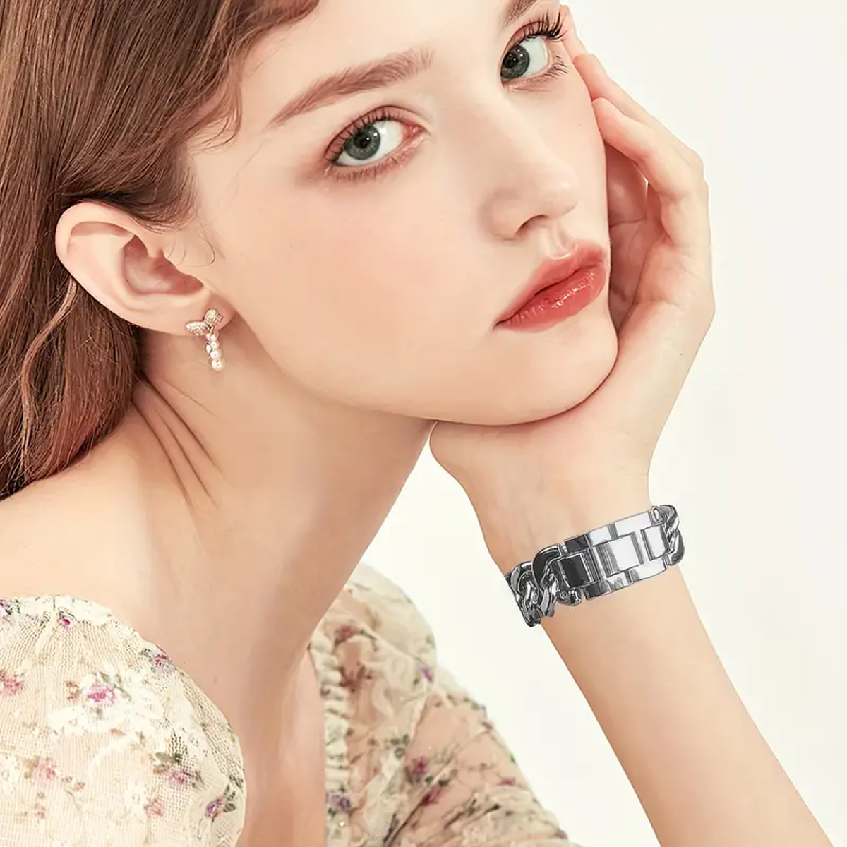 Die Hand einer Frau, die ein silbernes Armband trägt, ruht auf ihrem Kinn.