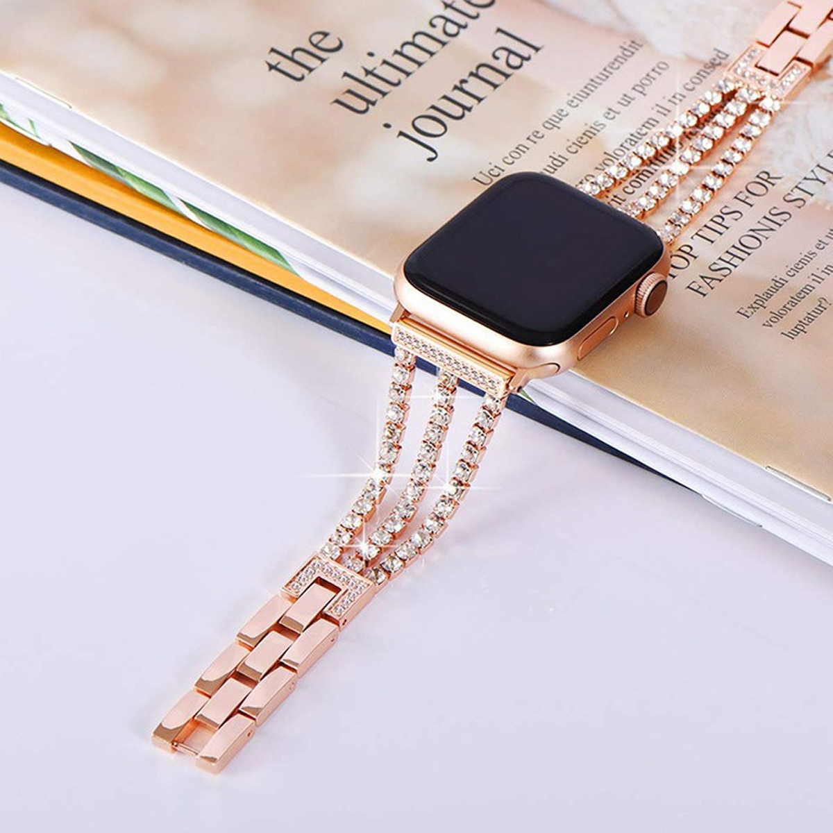Roségoldenes Armband mit funkelnden Juwelen, auf einem Journal.