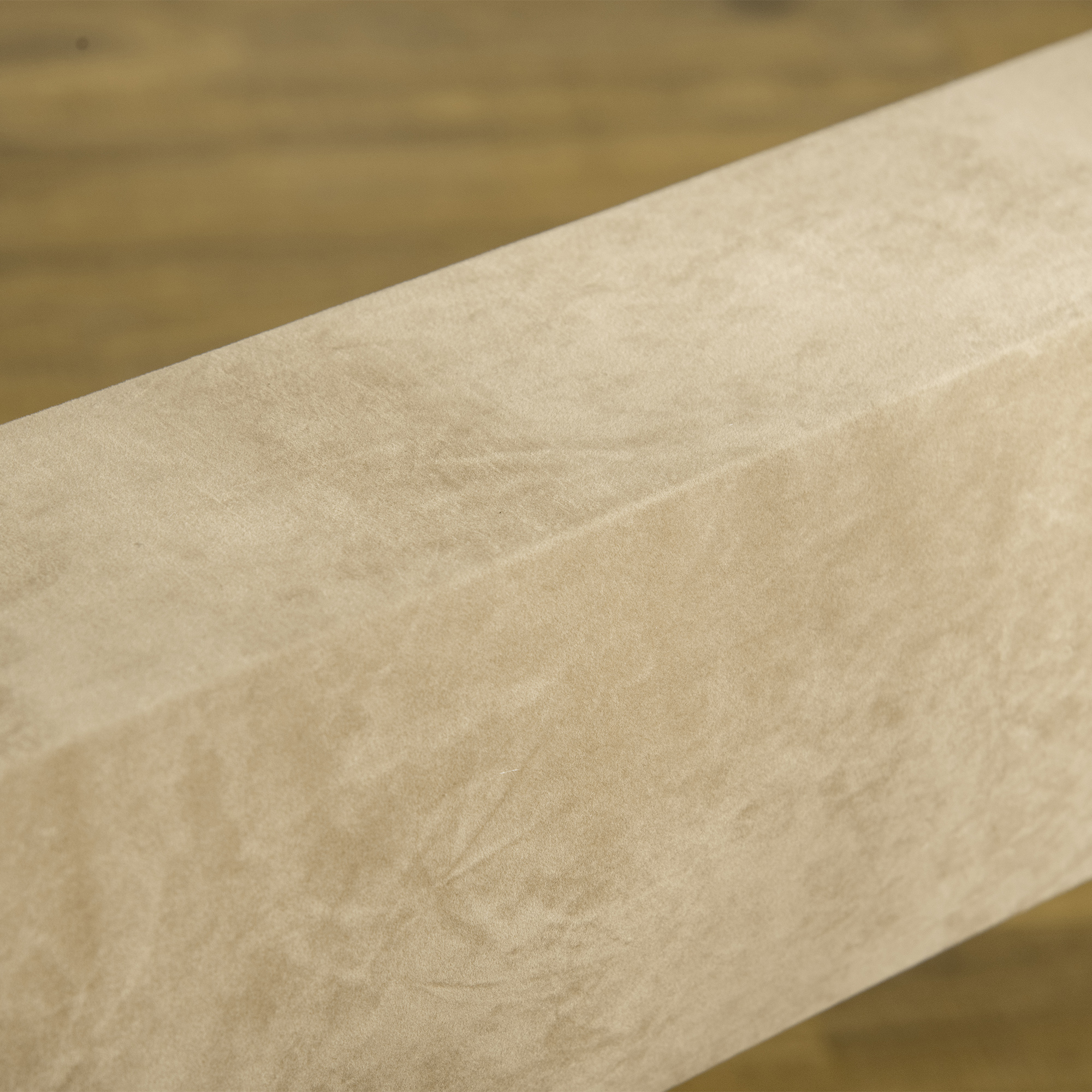 Un primo piano di una superficie rettangolare beige, possibilmente in legno o tessuto, con dettagli strutturati.