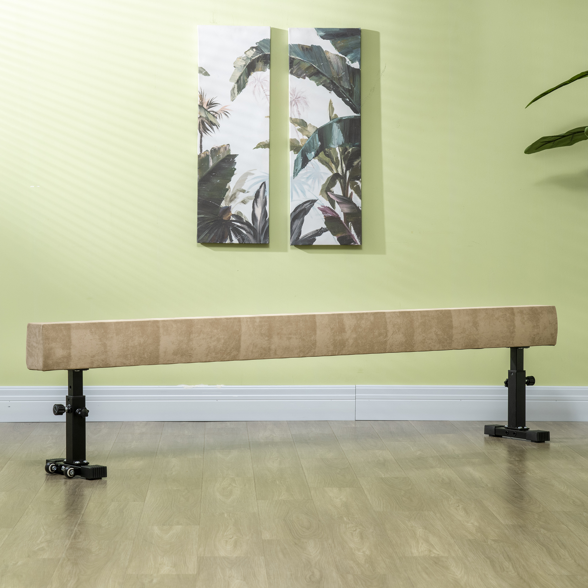 Trave di equilibrio su supporti neri, superficie in legno, parete verde con arte. Pavimento marrone.