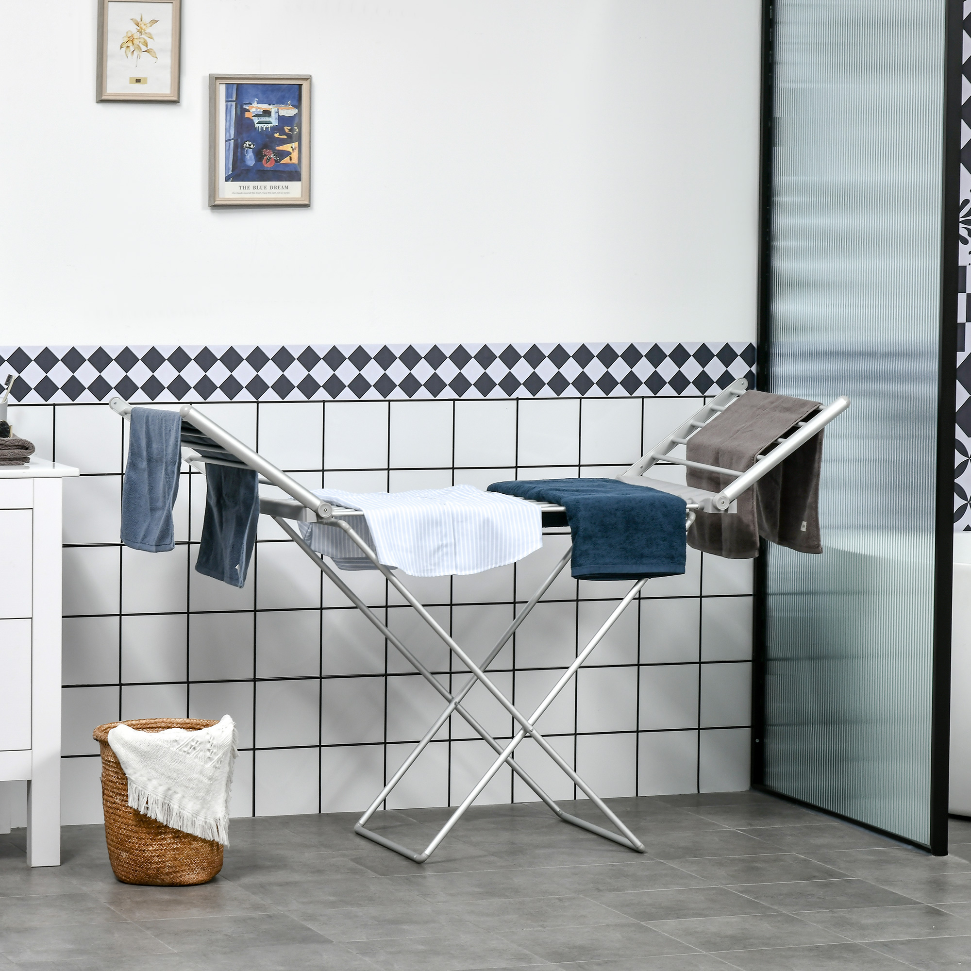 Uno stendibiancheria con asciugamani in un bagno. Sono visibili anche un cesto e opere d'arte.