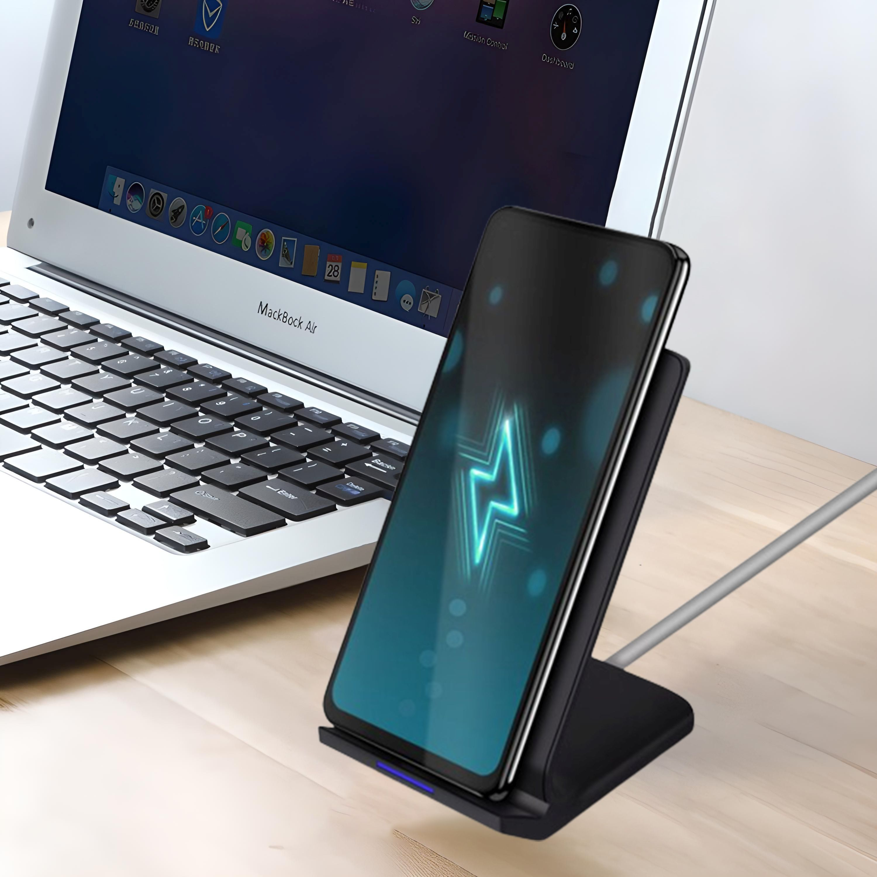 Telefon, das drahtlos auf einem Ständer geladen wird, mit Laptop im Hintergrund.