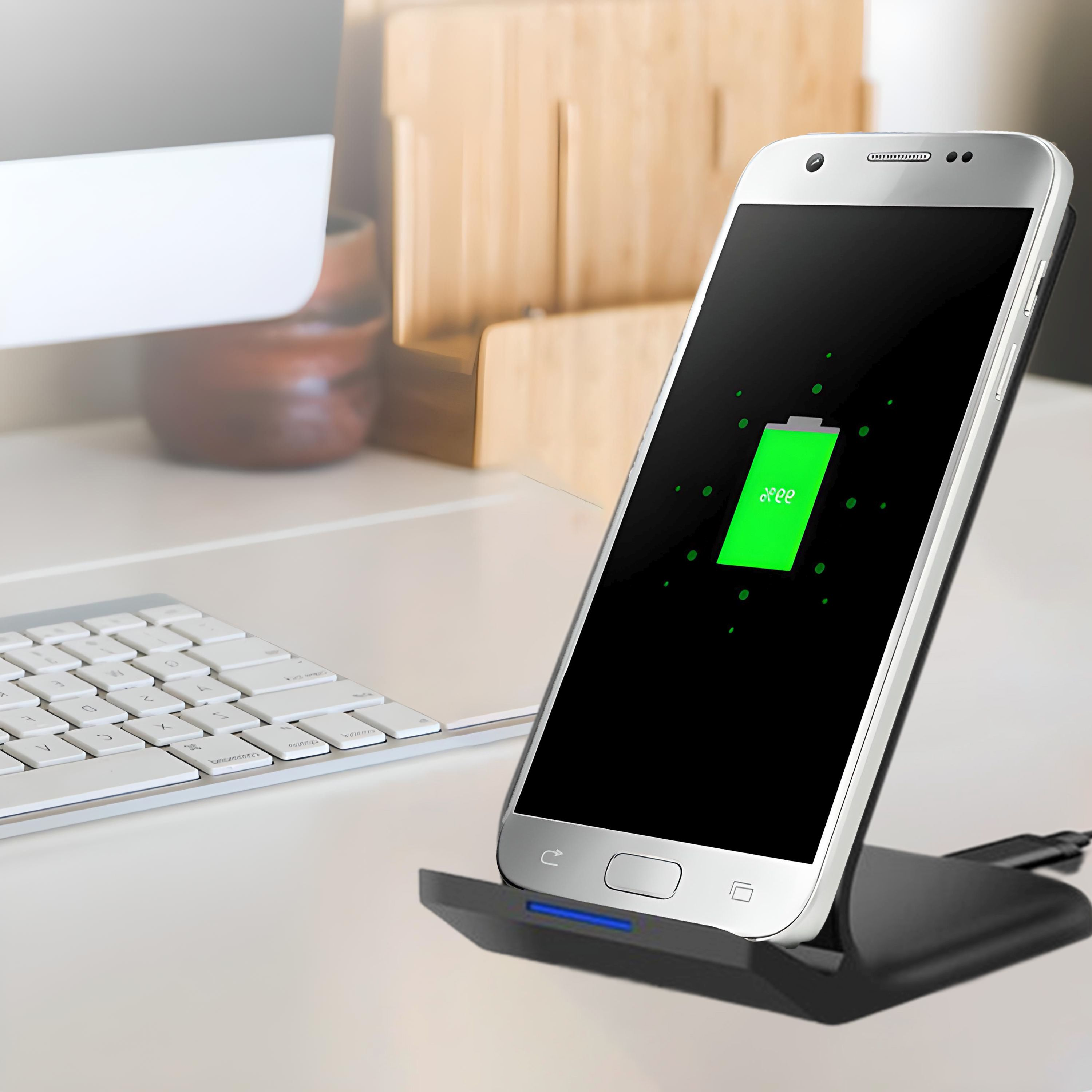 Ein silbernes Smartphone, das auf einem schwarzen kabellosen Ladepad aufgeladen wird.
