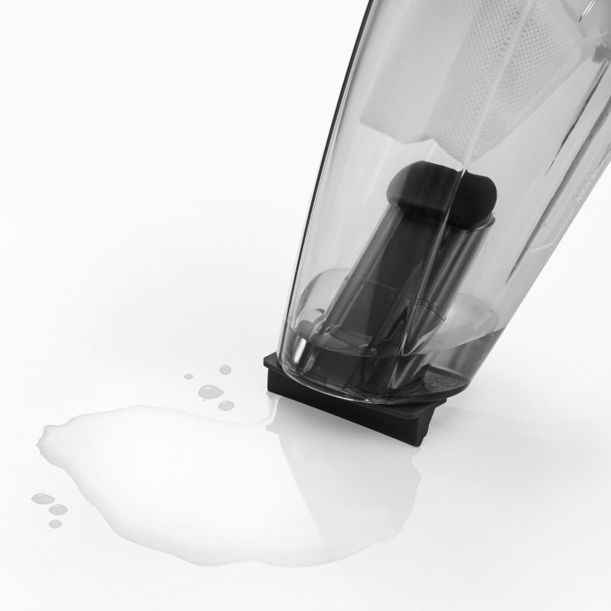 Parti di aspirapolvere nere e trasparenti. L'acqua si rovescia su una superficie bianca con riflessi.