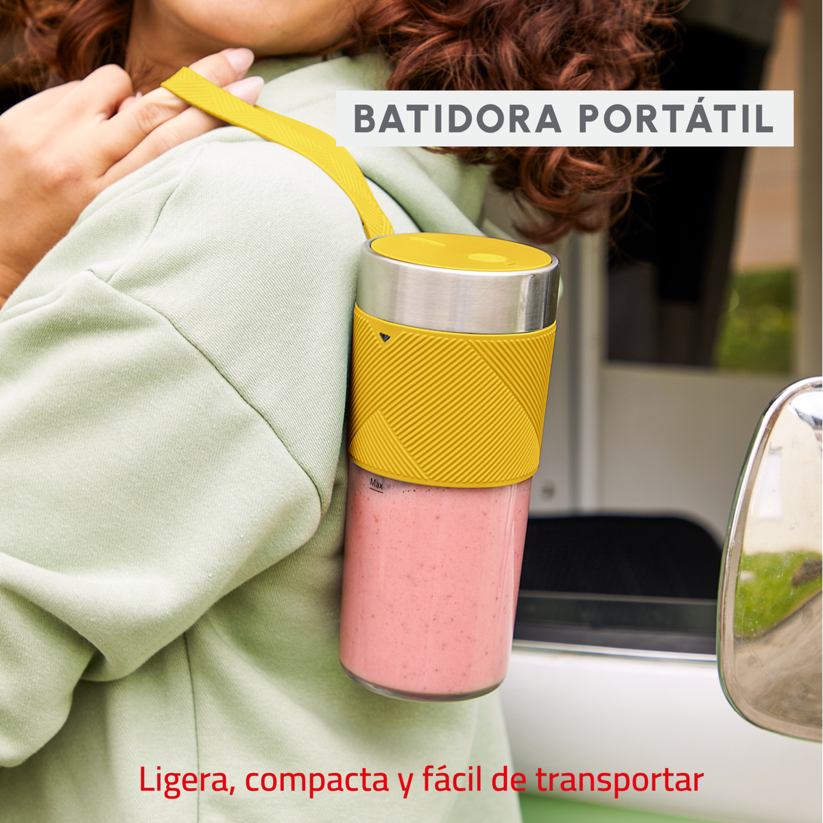 Donna che trasporta un frullatore portatile giallo. Frullato rosa visibile e testo.