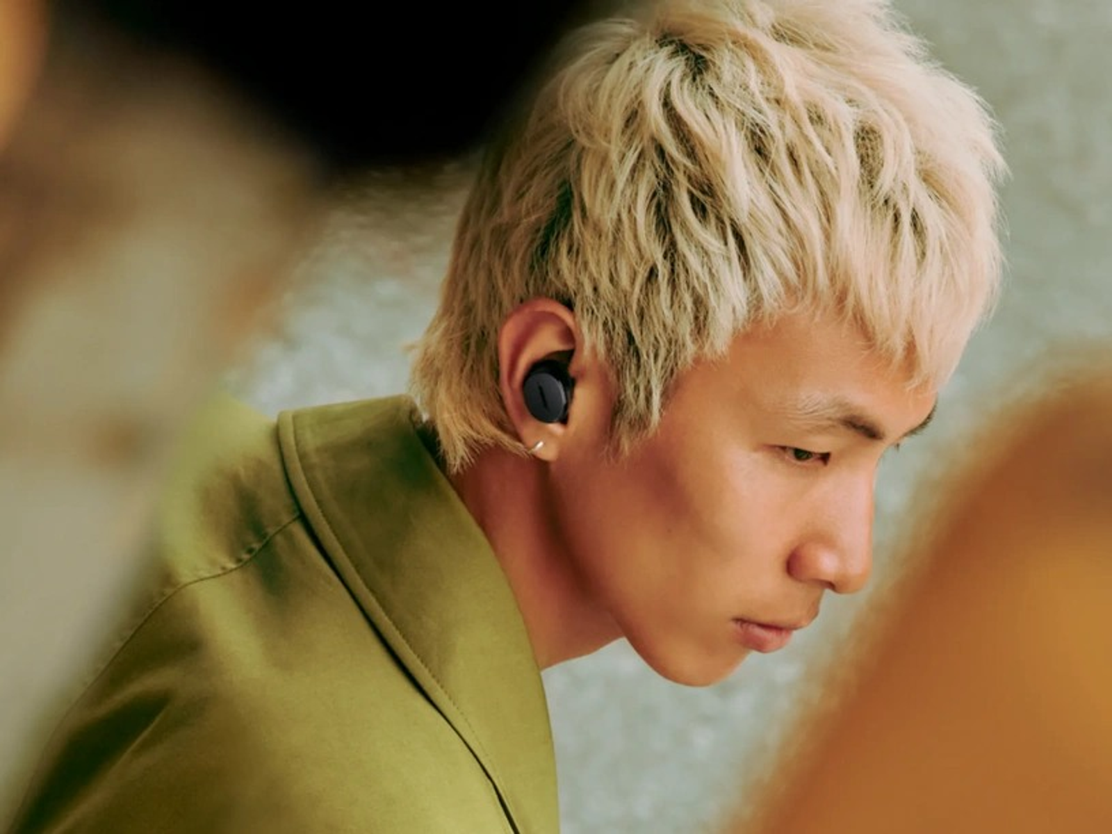 Joven con cabello rubio usando auriculares, en una toma de primer plano.