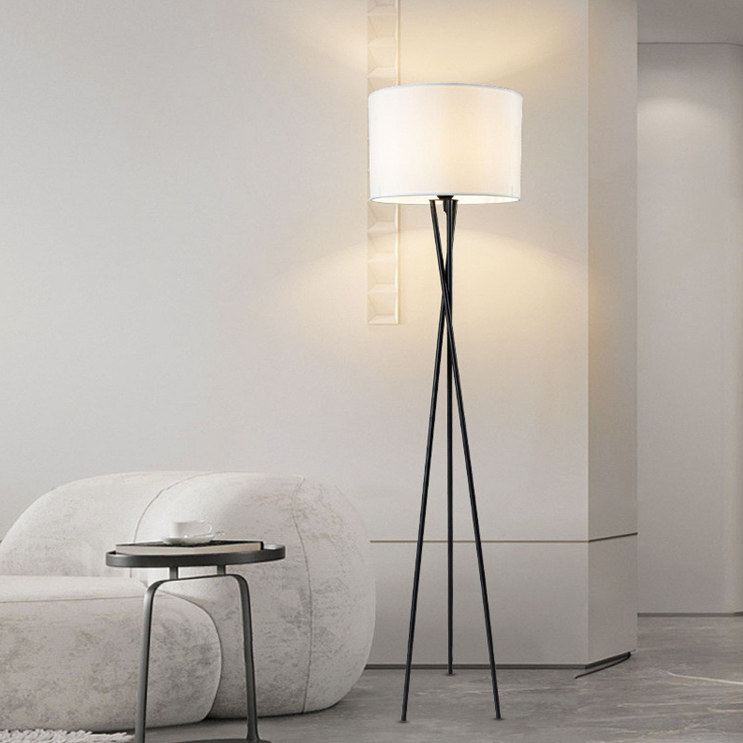 Hohe, schwarze Stehlampe mit weißem Lampenschirm, neben einem Beistelltisch und Sofa.