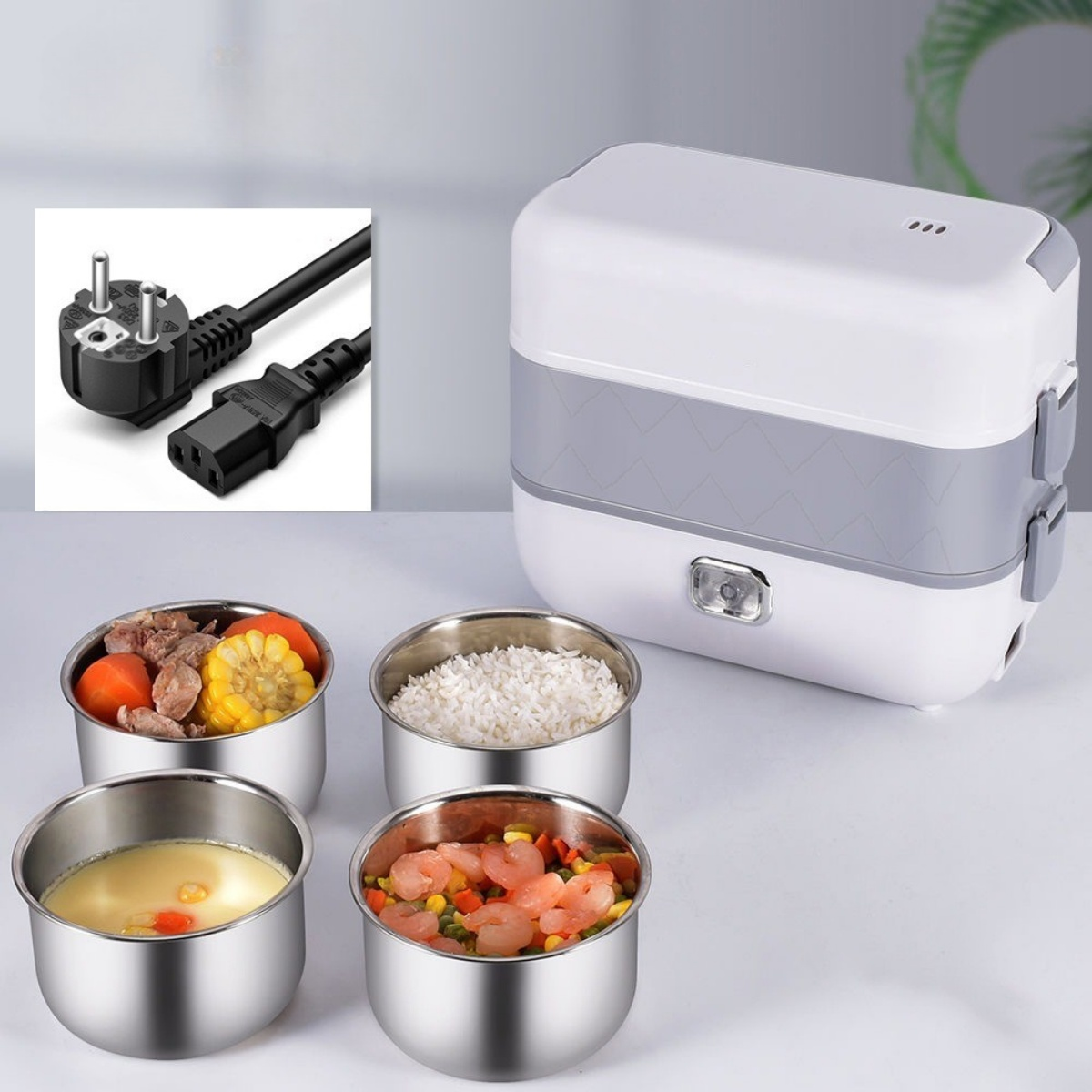 Lunchbox mit Lebensmittelbehältern, mit Essen darin und einem Stecker. Auf weißer Oberfläche.