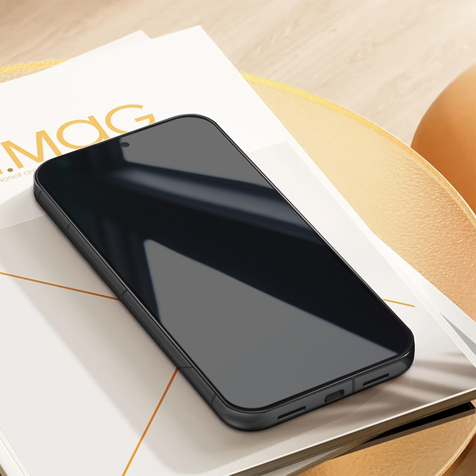 Smartphone nero su una superficie dorata. Una rivista è sotto il telefono.
