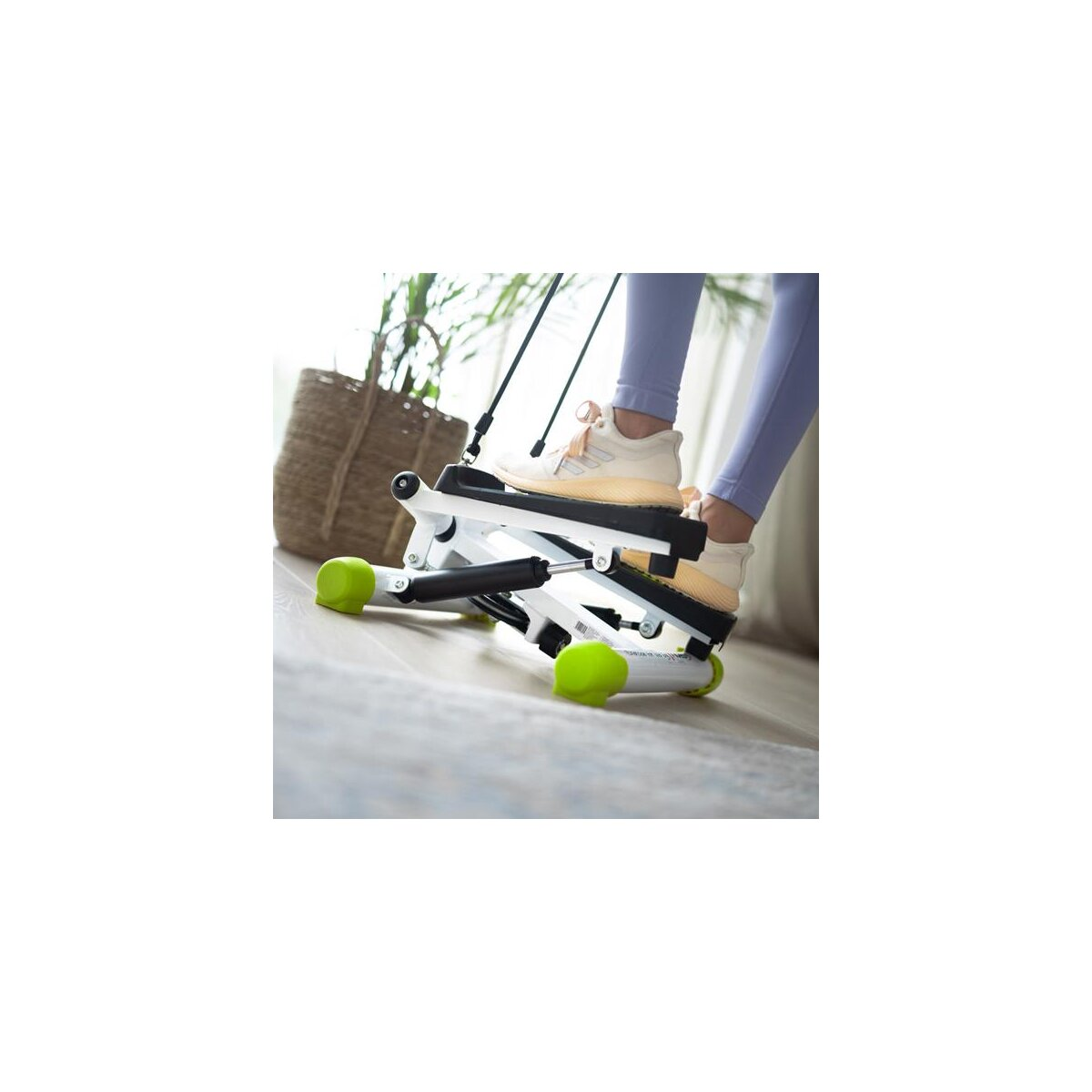 Eine Person benutzt drinnen eine Stepper-Maschine. Eine Pflanze ist im Hintergrund.