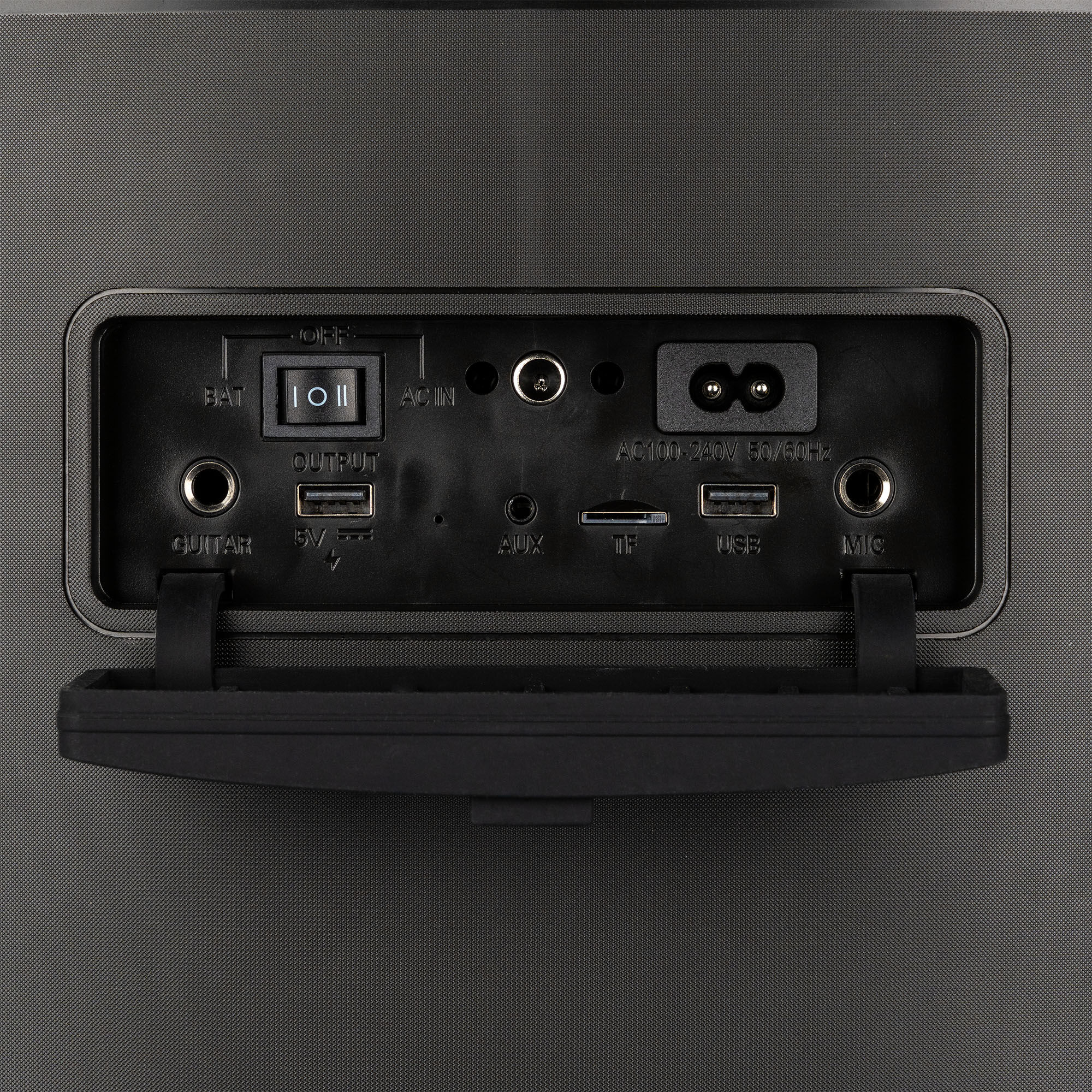 Panel trasero de un altavoz negro con varios puertos de entrada/salida y controles. Fondo gris.