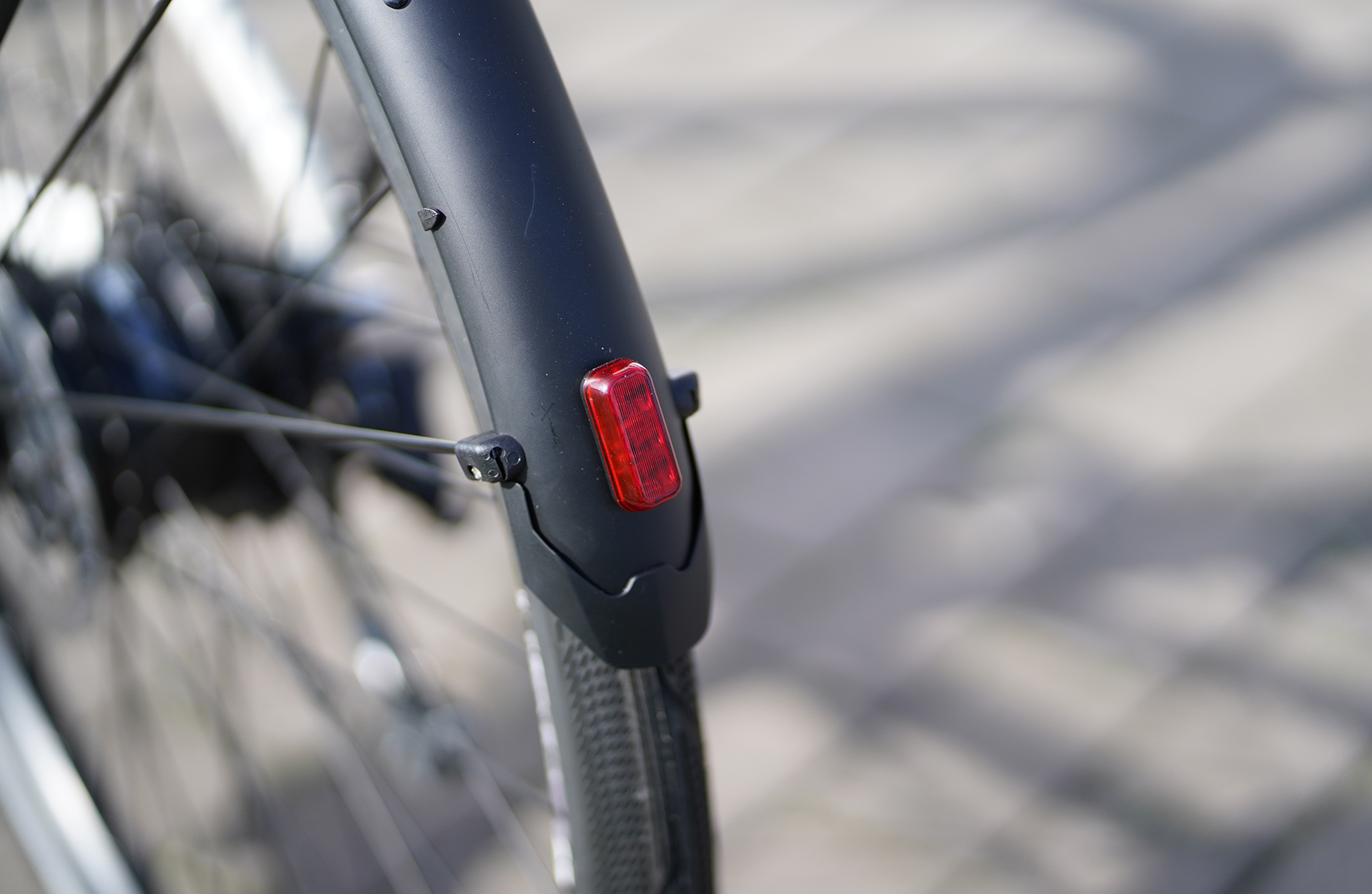 Rücklicht an einem Fahrradkotflügel mit Radspeichen im Hintergrund.