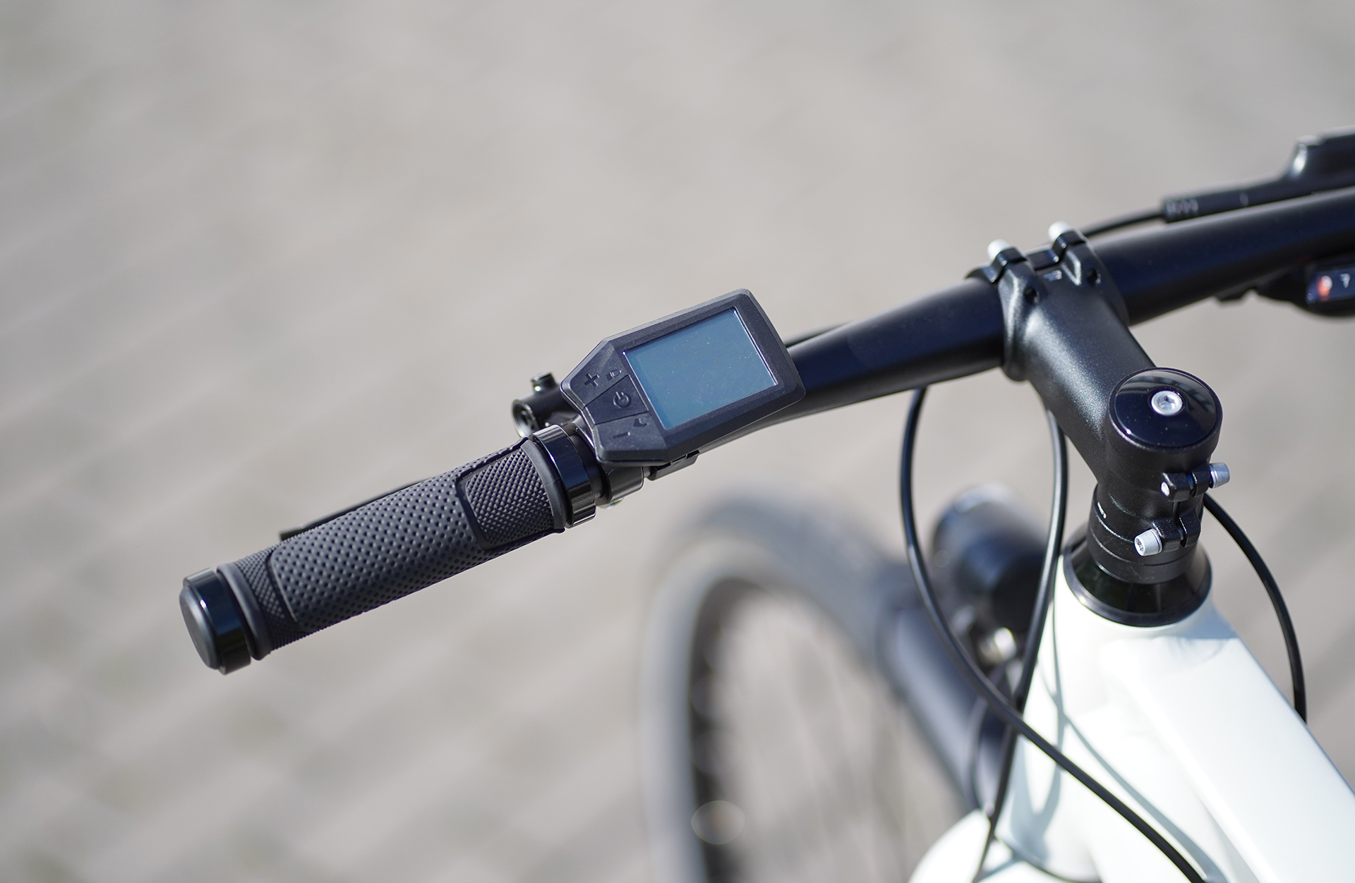Nahaufnahme eines Fahrradlenkers mit Digitalanzeige und schwarzen Griffen.