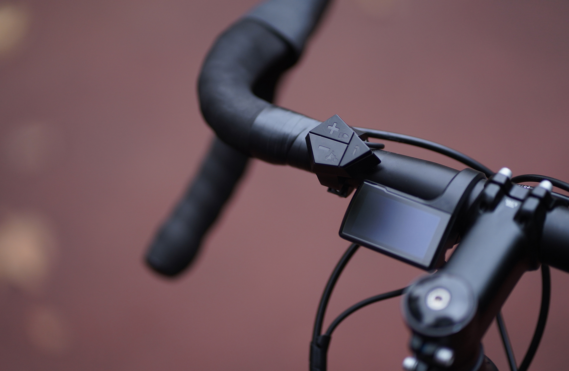 Nahaufnahme des Lenkers eines Fahrrads mit einem kleinen digitalen Display und Bedienelementen.